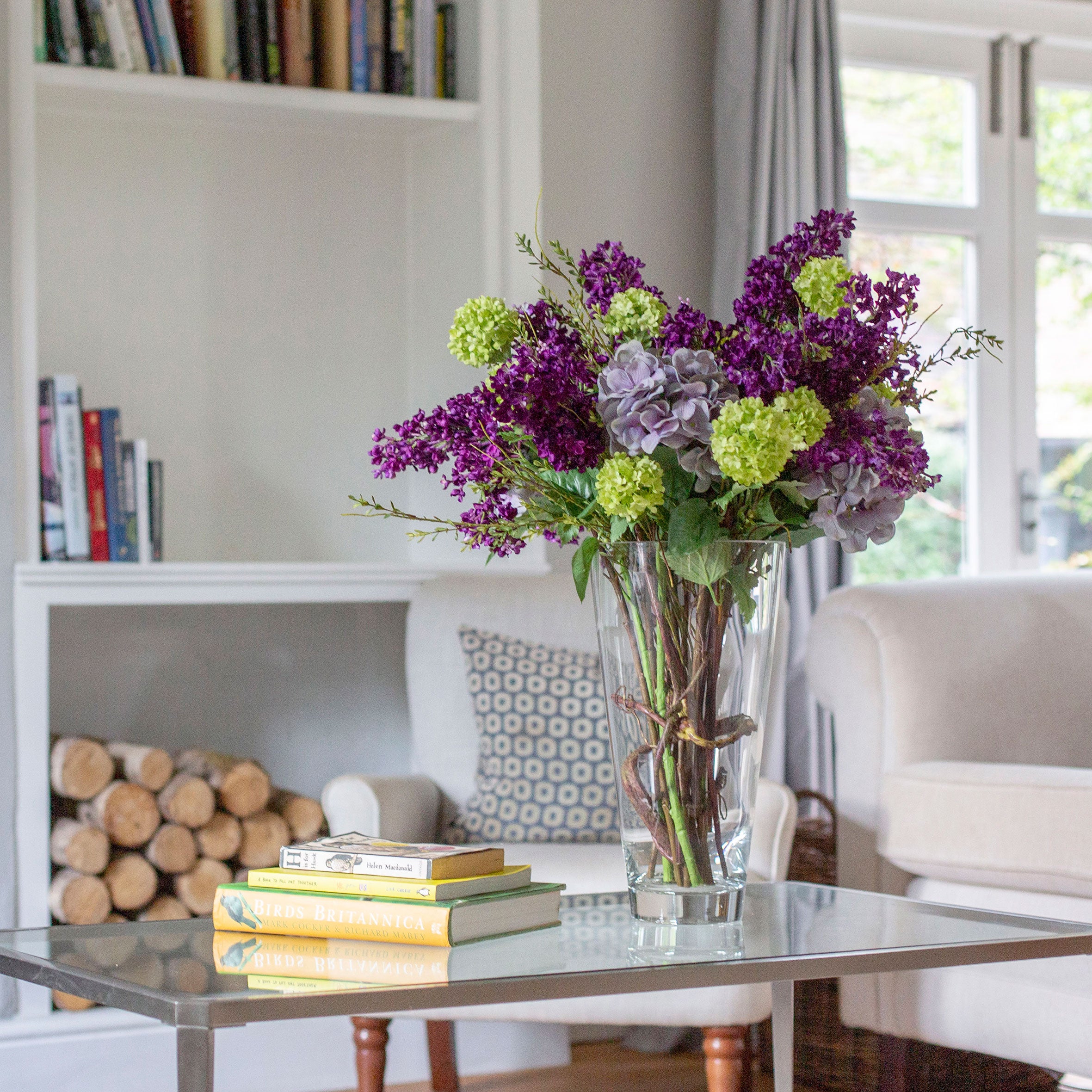 Artificial lilac and viburnum arrangement in a clear glass vase