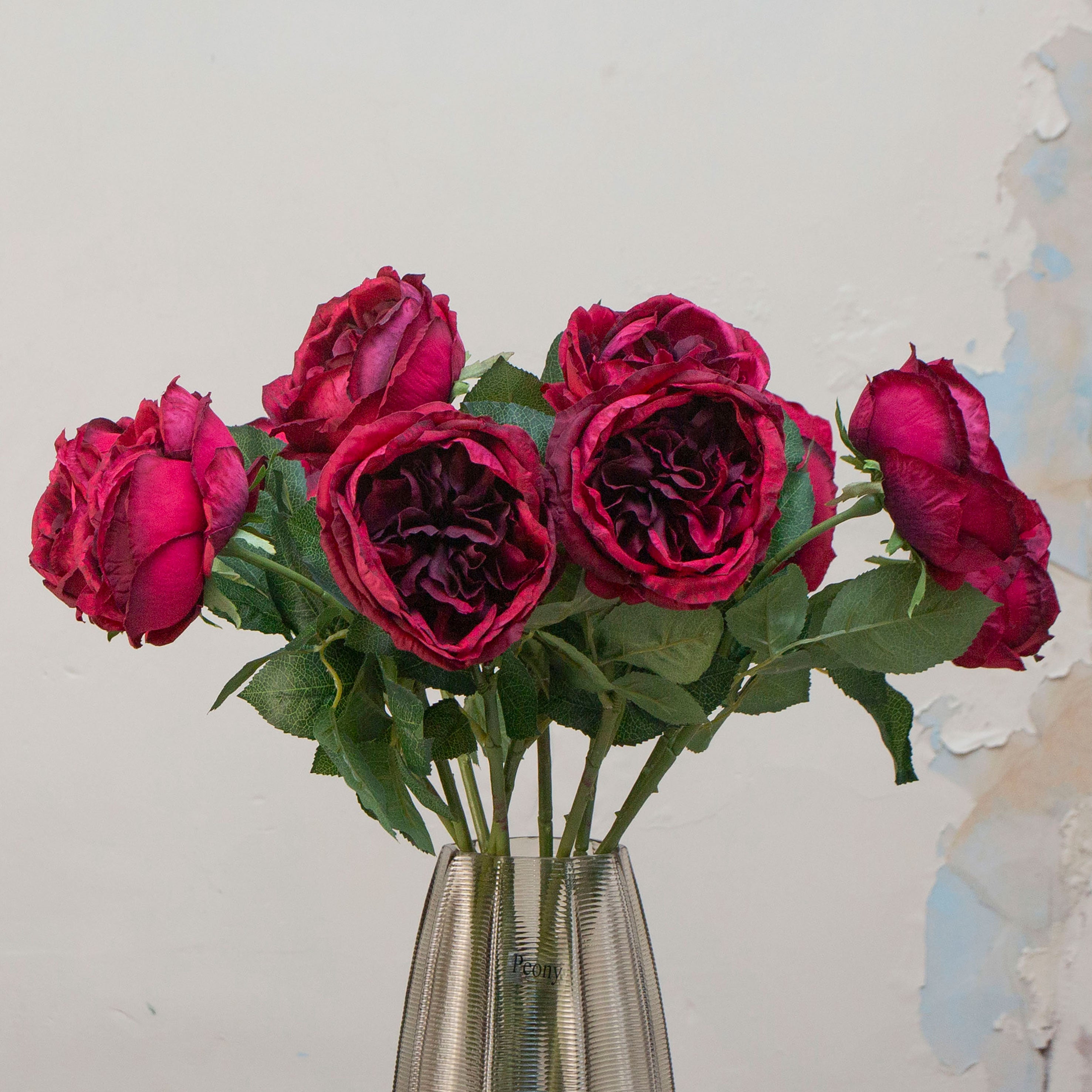 Close-up of artificial rose flower, showing deep red burgundy petals with layered texture, subtle tonal variation and realistic detailing.