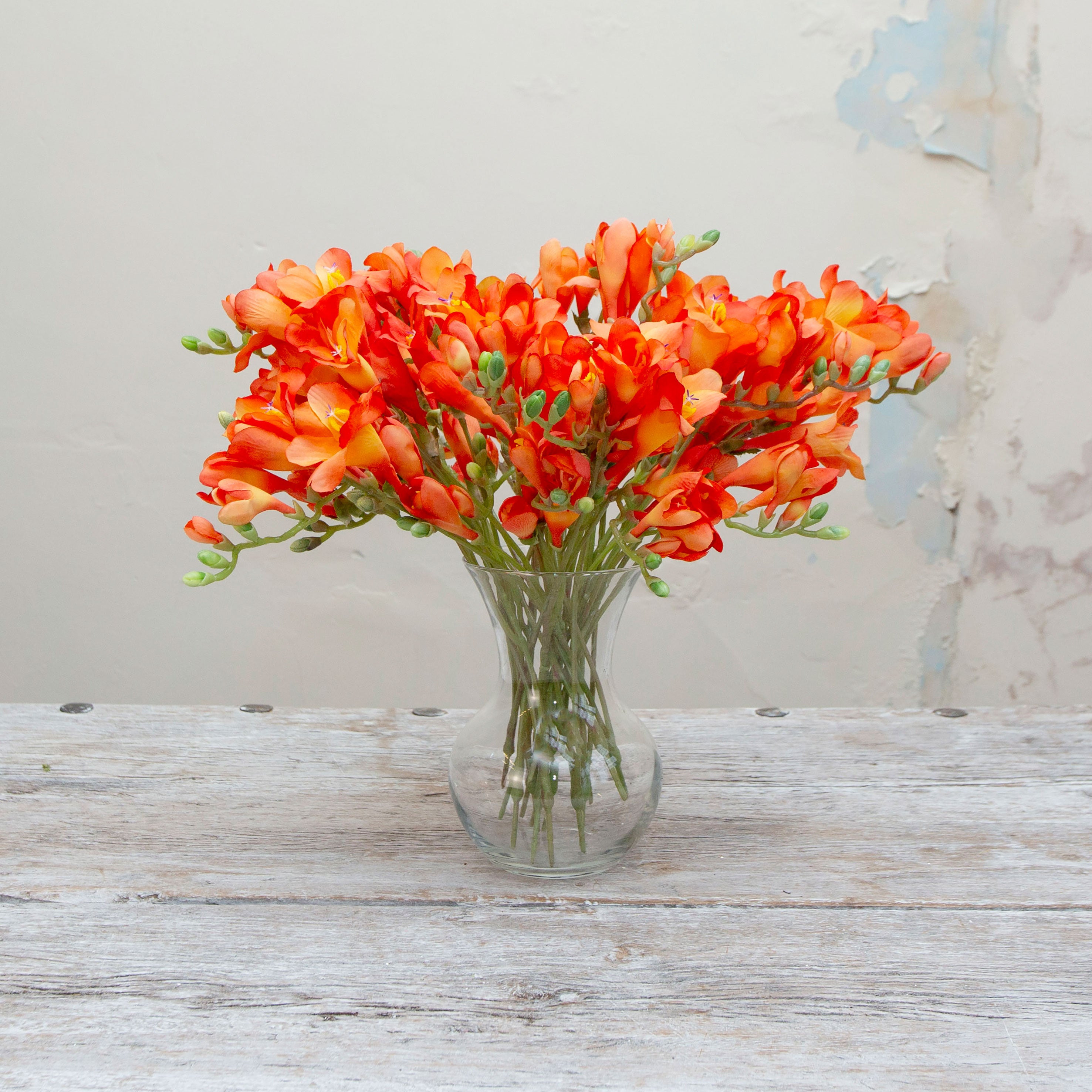Artificial orange freesia stem displayed in a vase for styling inspiration