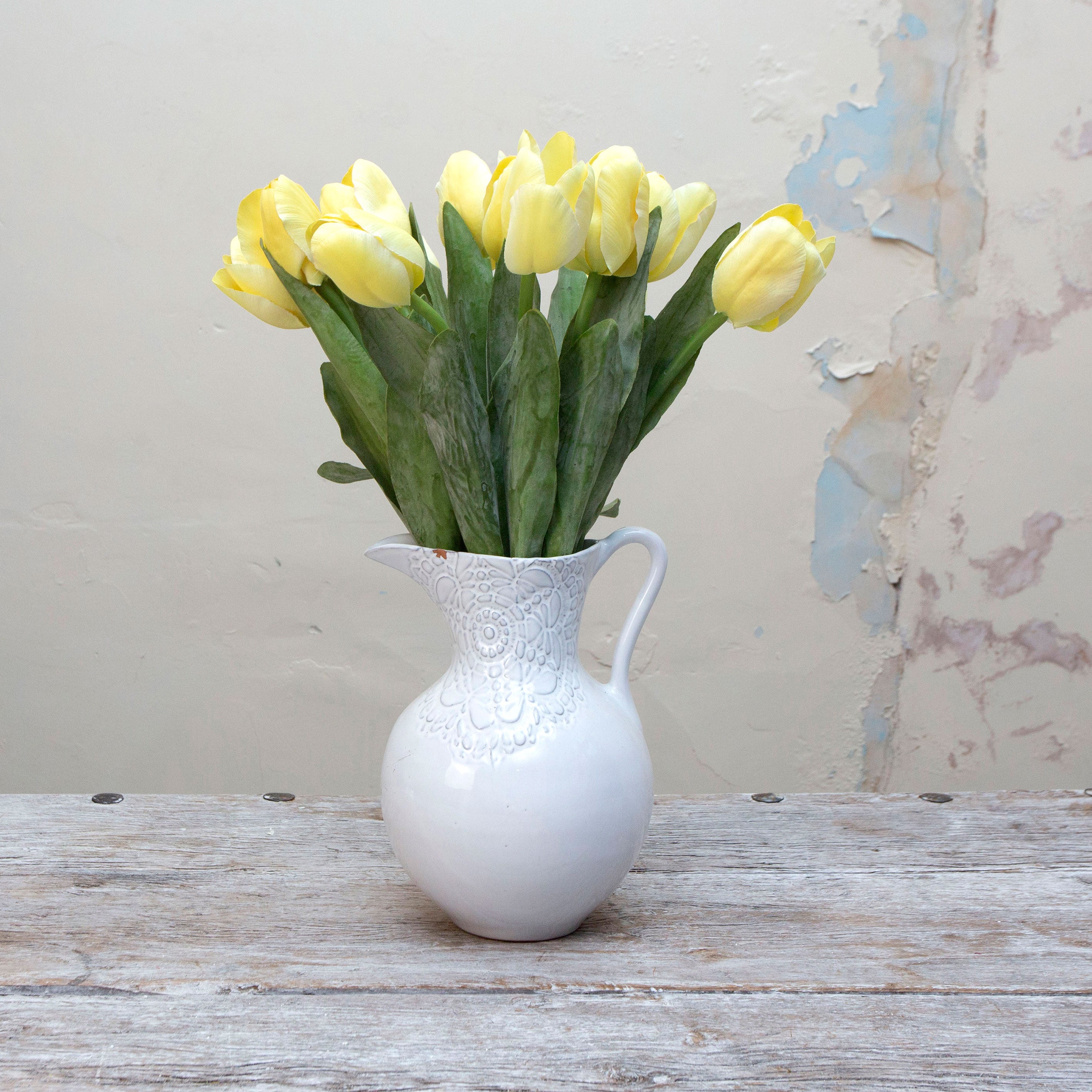 Artificial yellow tulip stems displayed together in a vase for styling purposes.