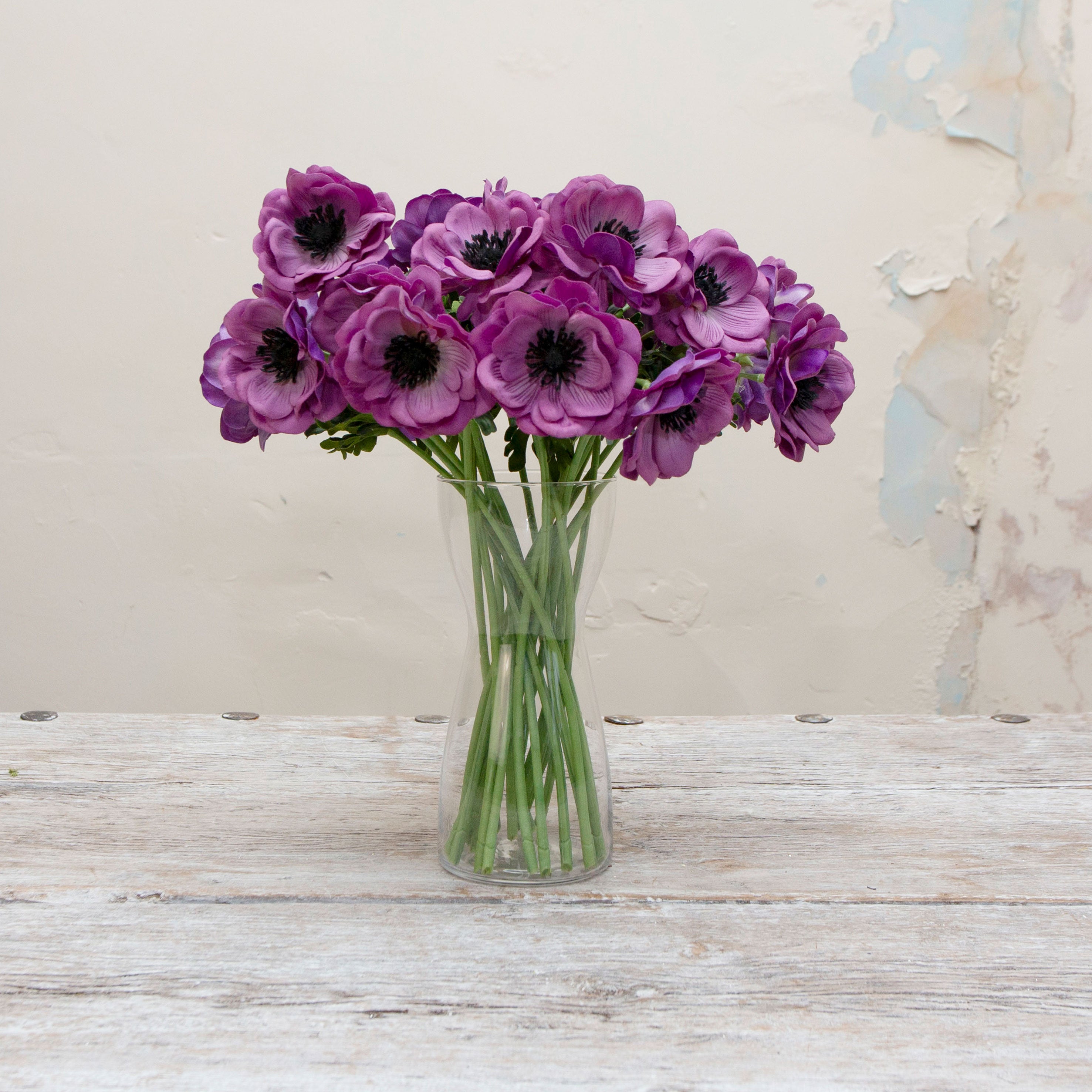 Artificial purple anemone stems displayed together in a vase for styling purposes.