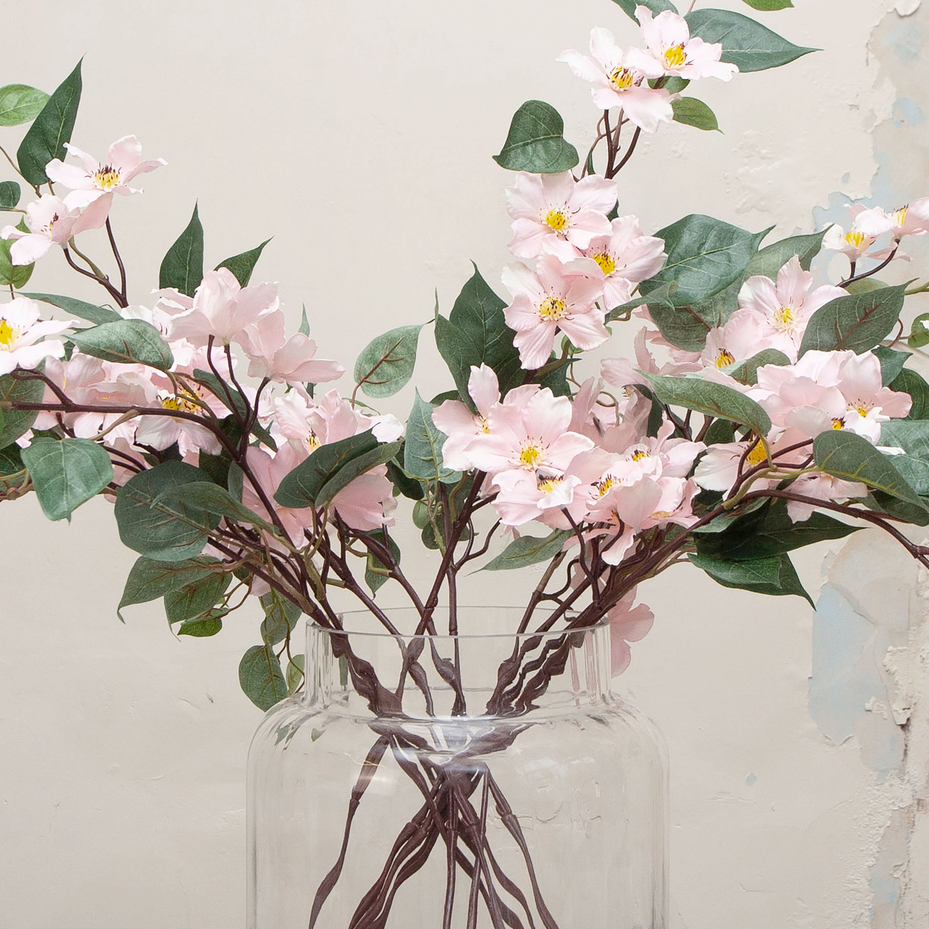Close-up of artificial pale pink clematis flowers, highlighting star-shaped petals, gentle colour variation, soft yellow centres and fine stem detailing