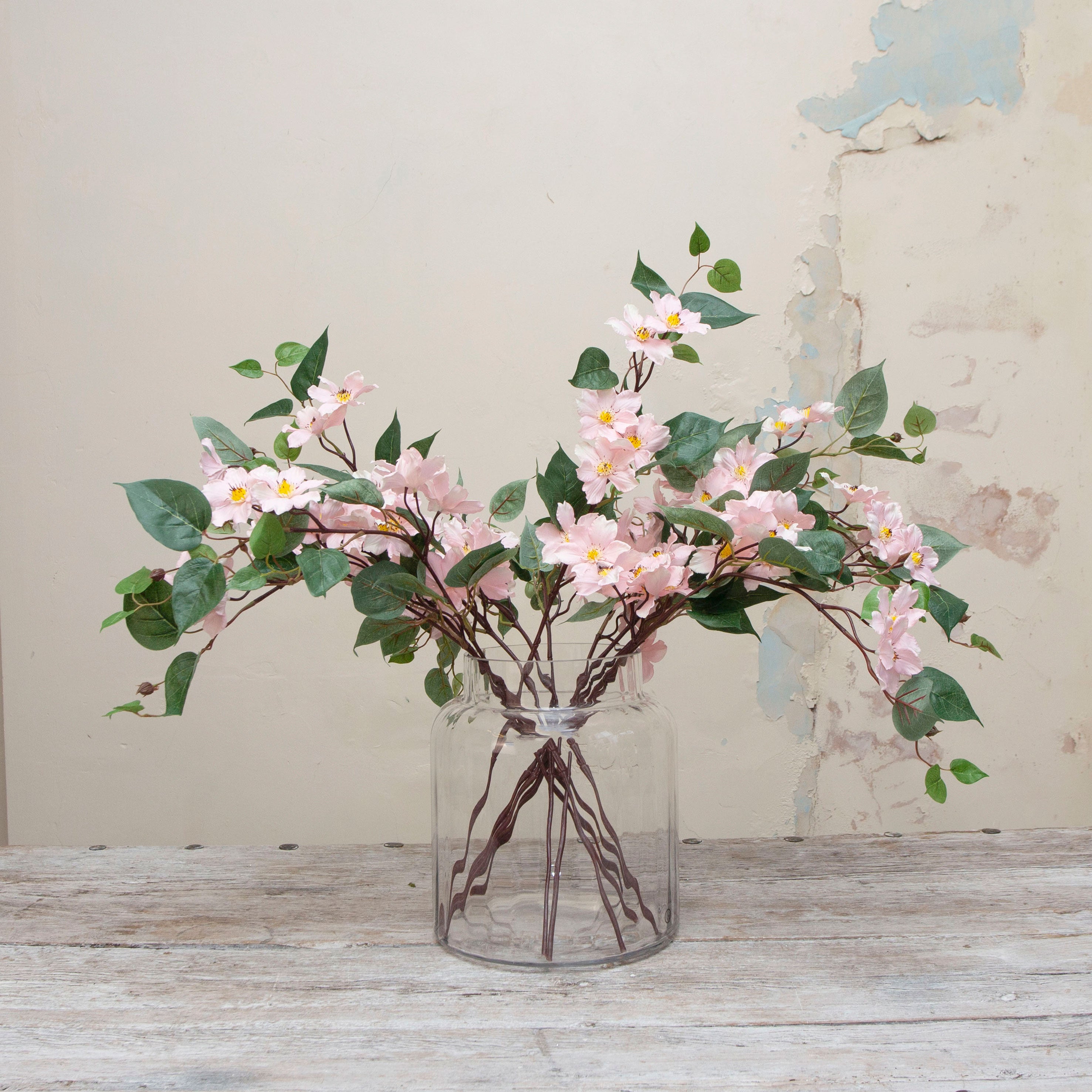 Artificial pale pink clematis stem displayed in a vase, showing delicate climbing-style stems, airy pink blooms and natural foliage for an elegant, romantic arrangement