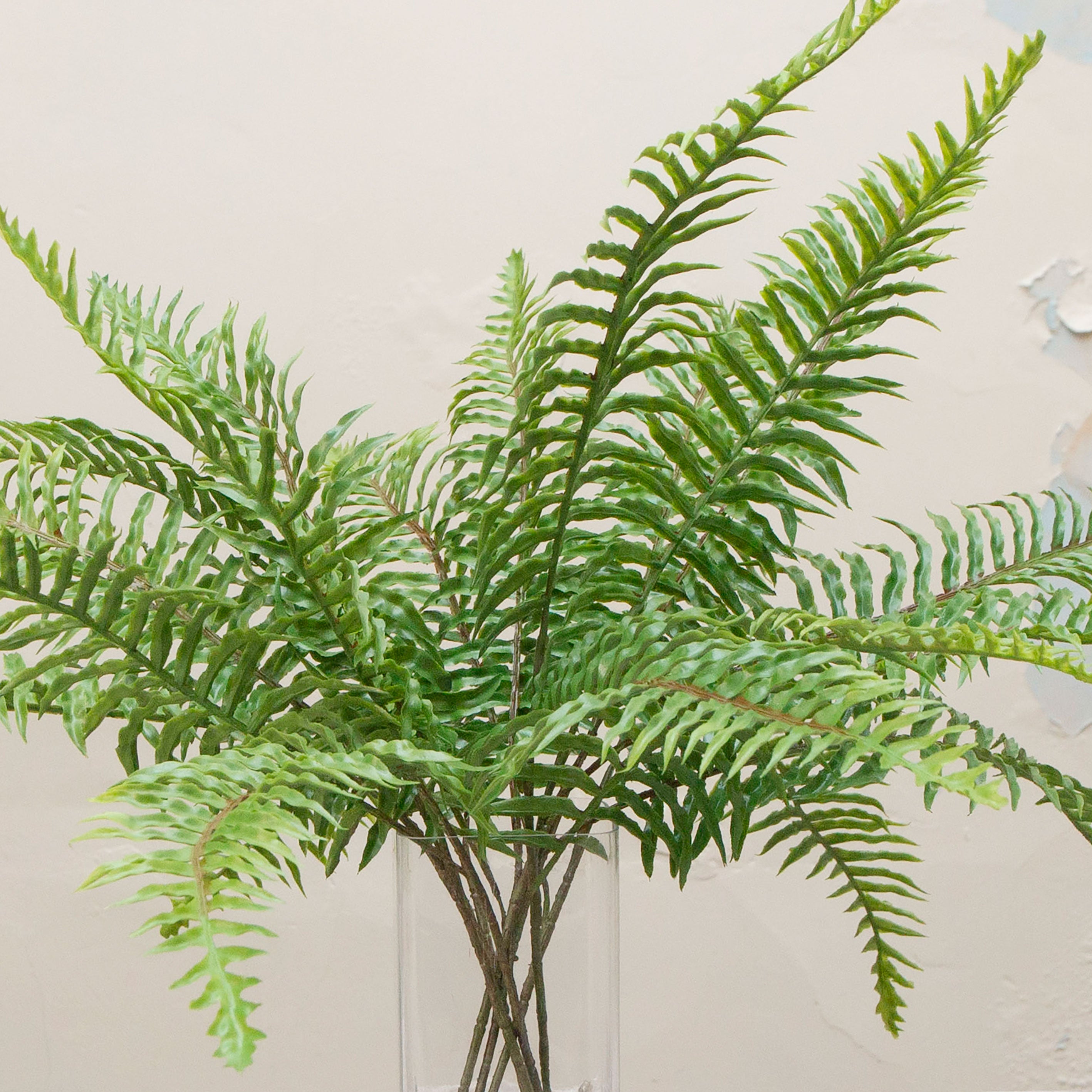 lose-up of artificial green fern spray foliage showing detailed fronds and texture.