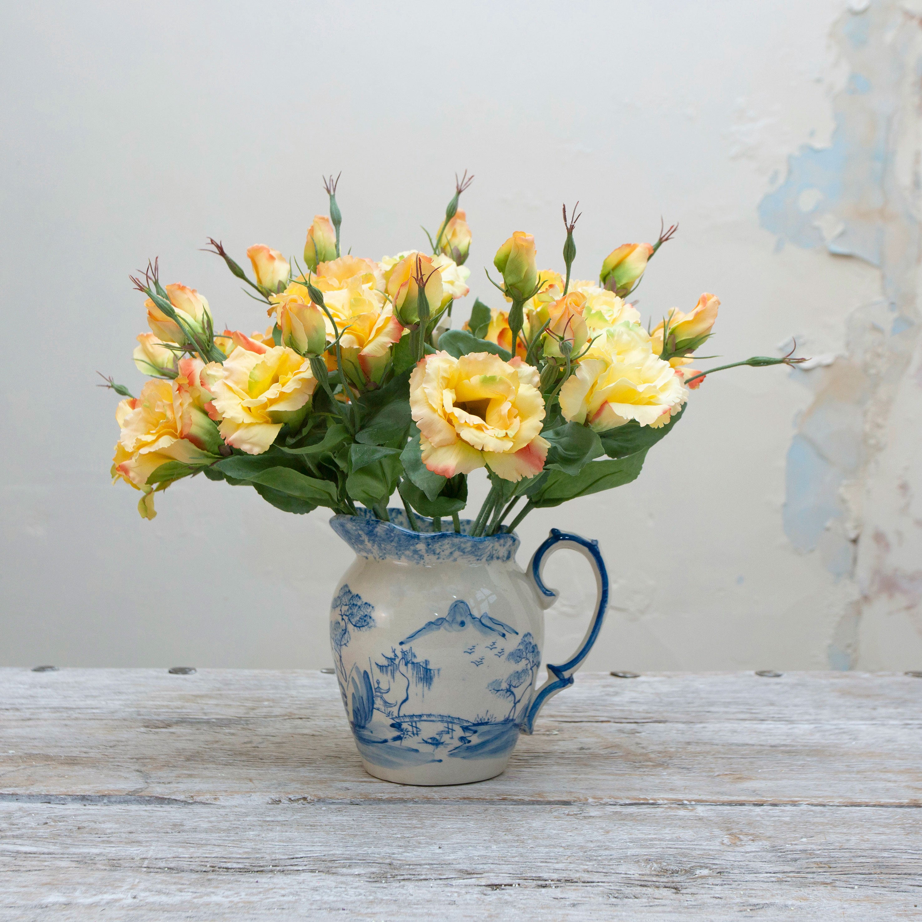 Artificial yellow lisianthus picks with soft peach edging displayed together in a vase for styling purposes