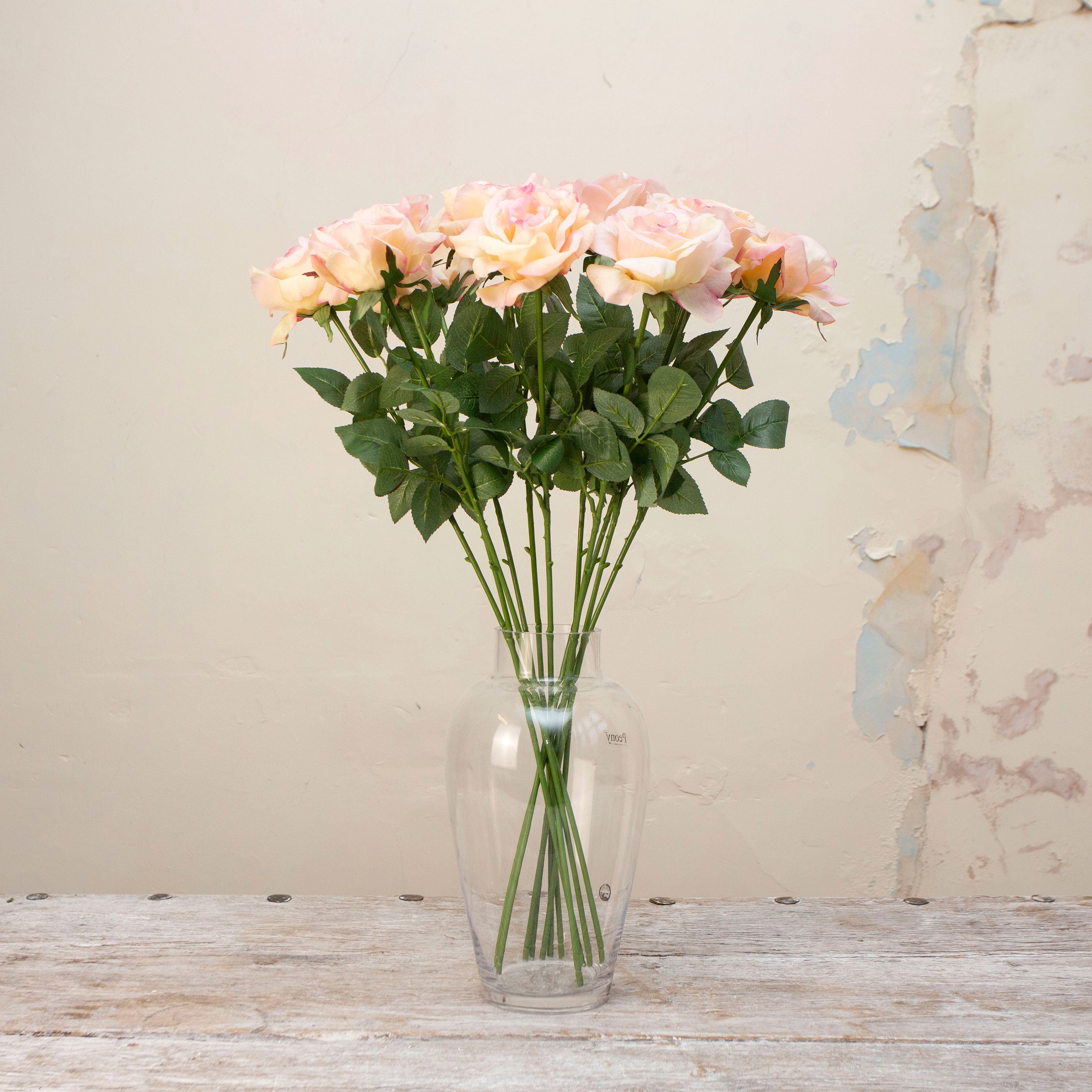 Artificial peach rose stem displayed in a vase, showcasing an open rose flower with layered peach petals, subtle colour variation and natural-looking foliage