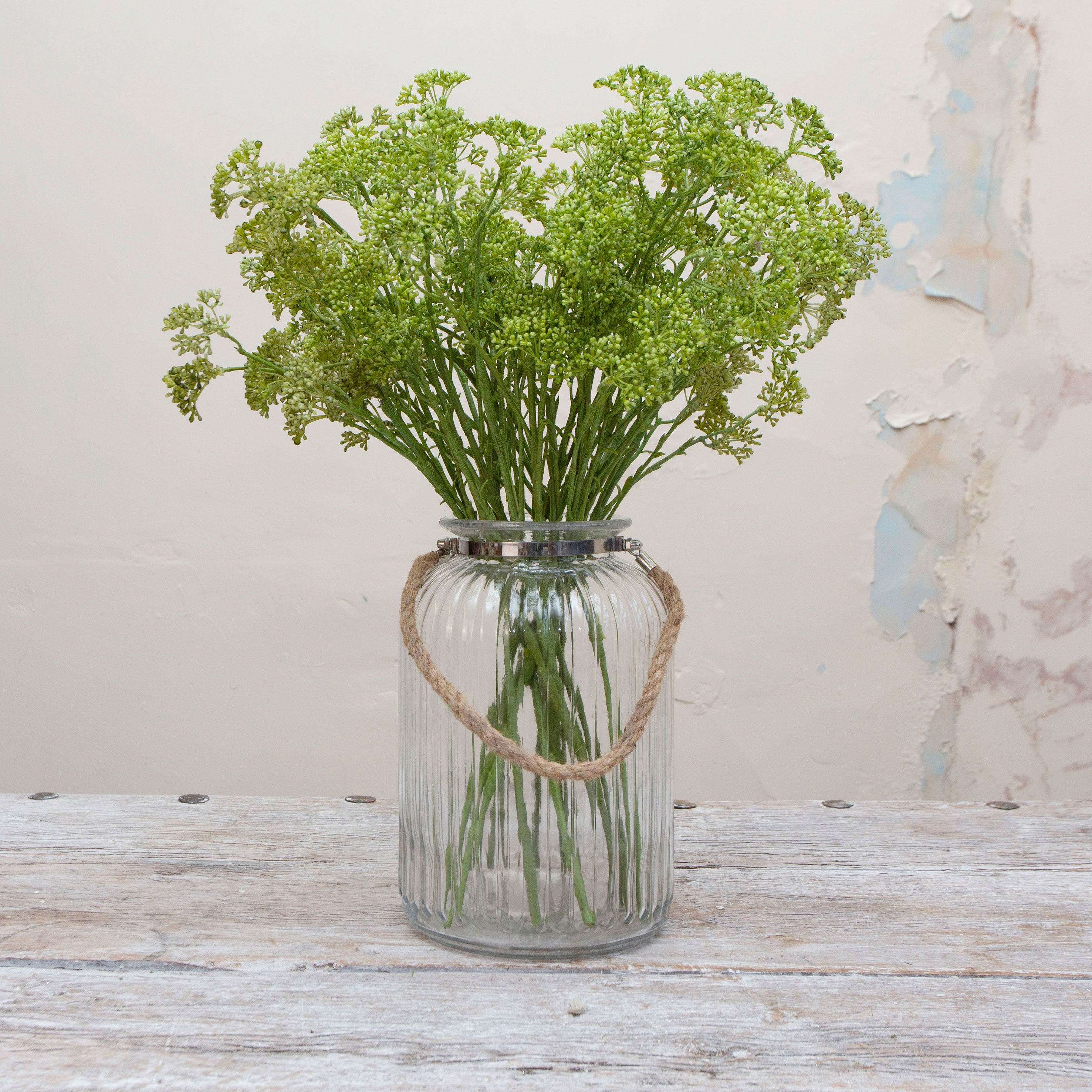 Artificial green patrinia stems displayed together in a clear glass vase for styling purposes.