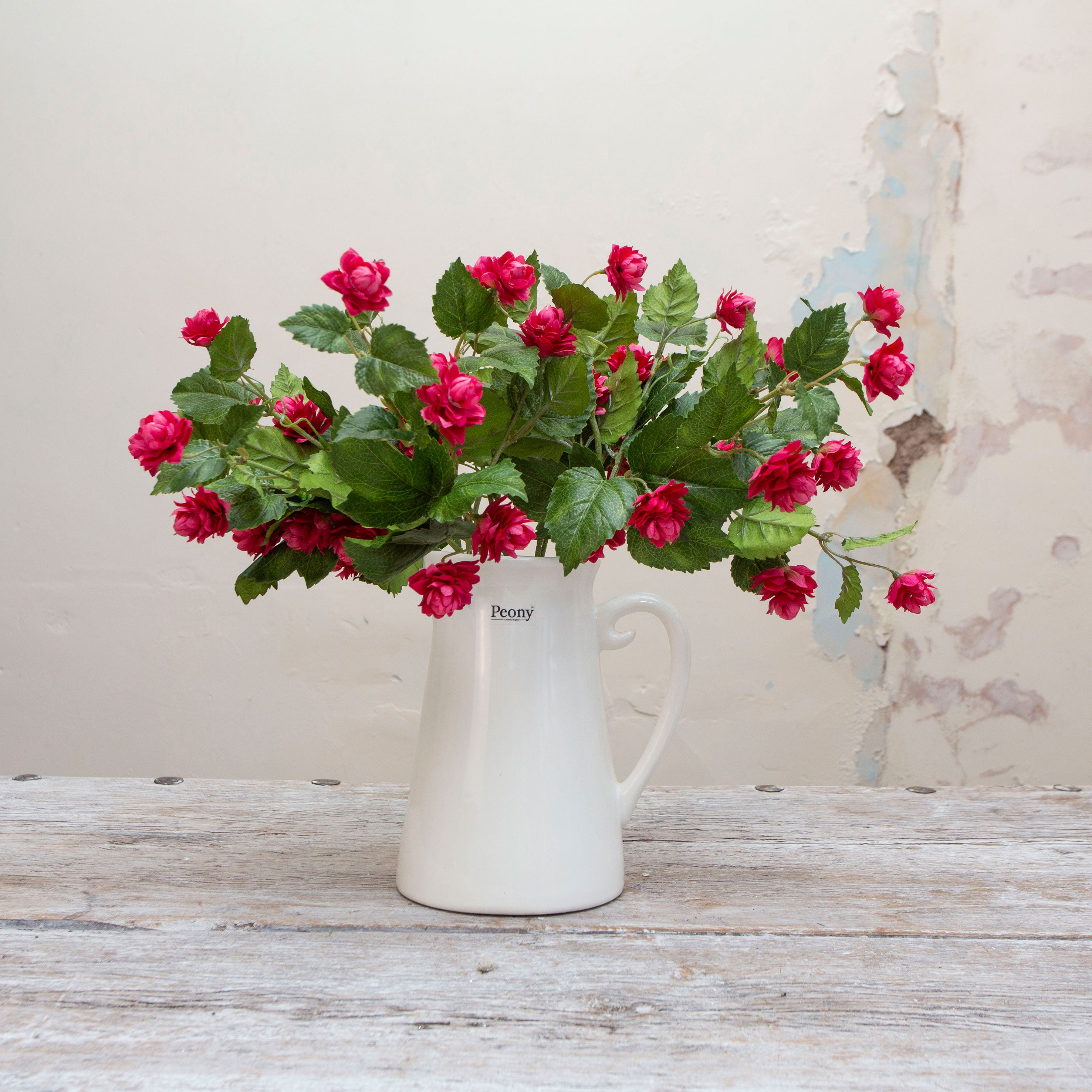 Artificial fuchsia hop spray stems displayed together in a vase with pink blooms and green foliage