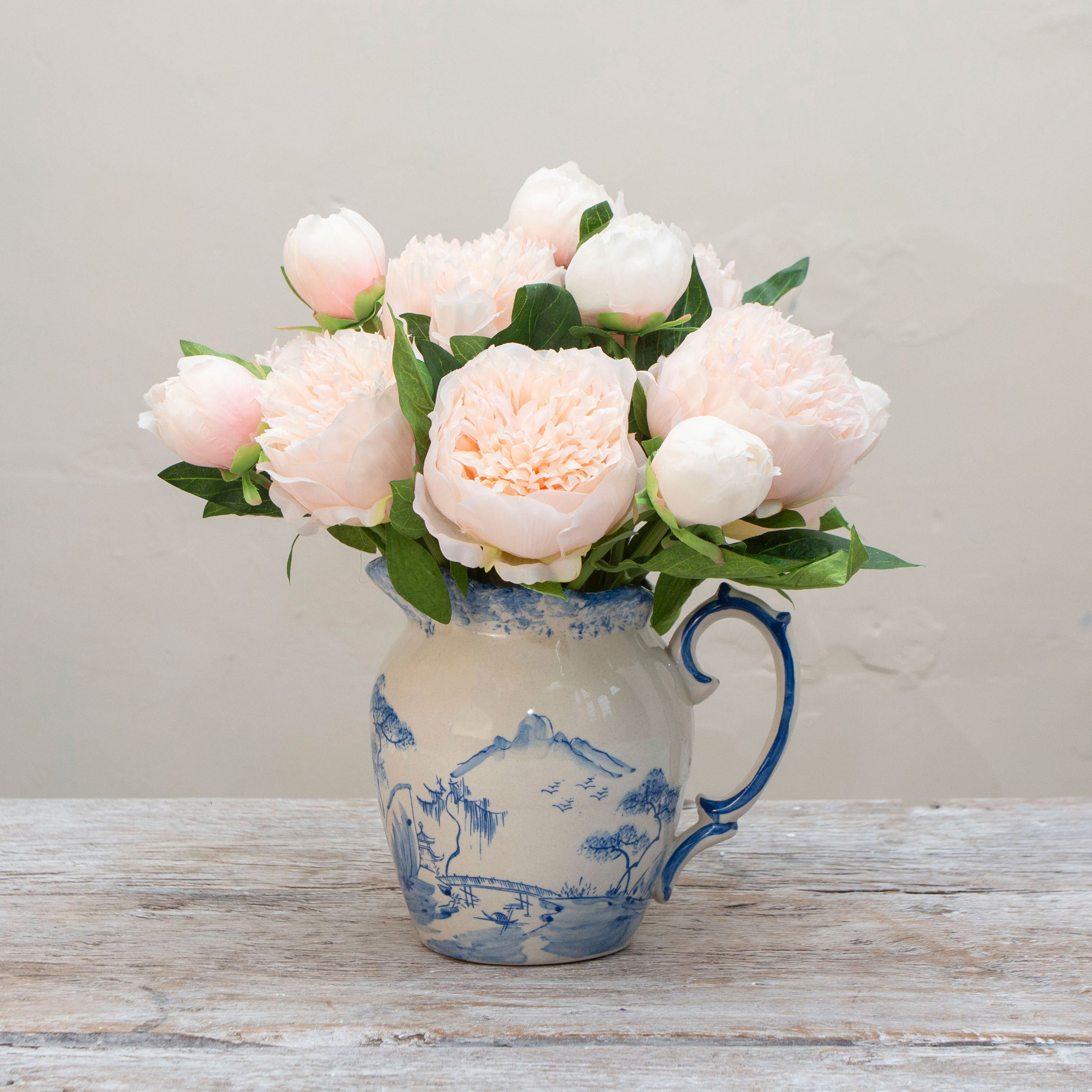 Artificial soft blush peach peony stems displayed together in a vase for styling purposes.