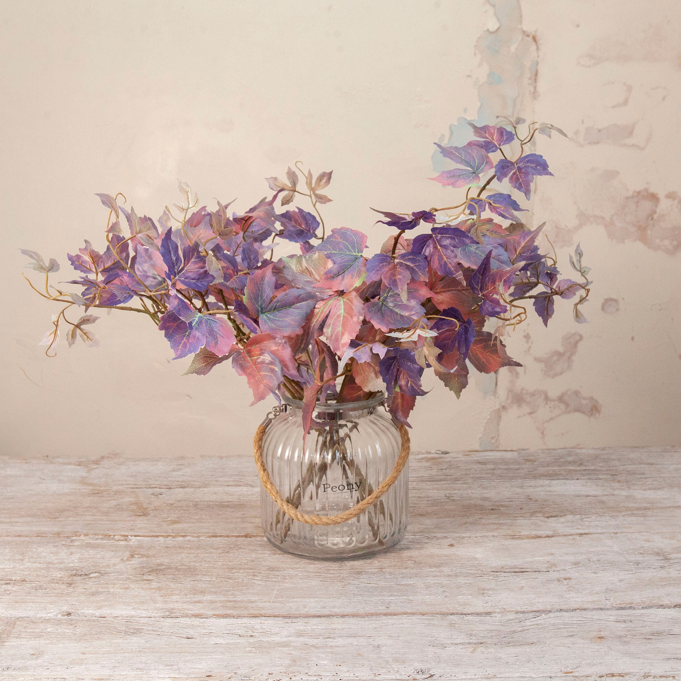 Artificial Leaf Foliage Stems with trailing purple, burgundy and muted autumn-toned leaves displayed in a clear ribbed glass vase