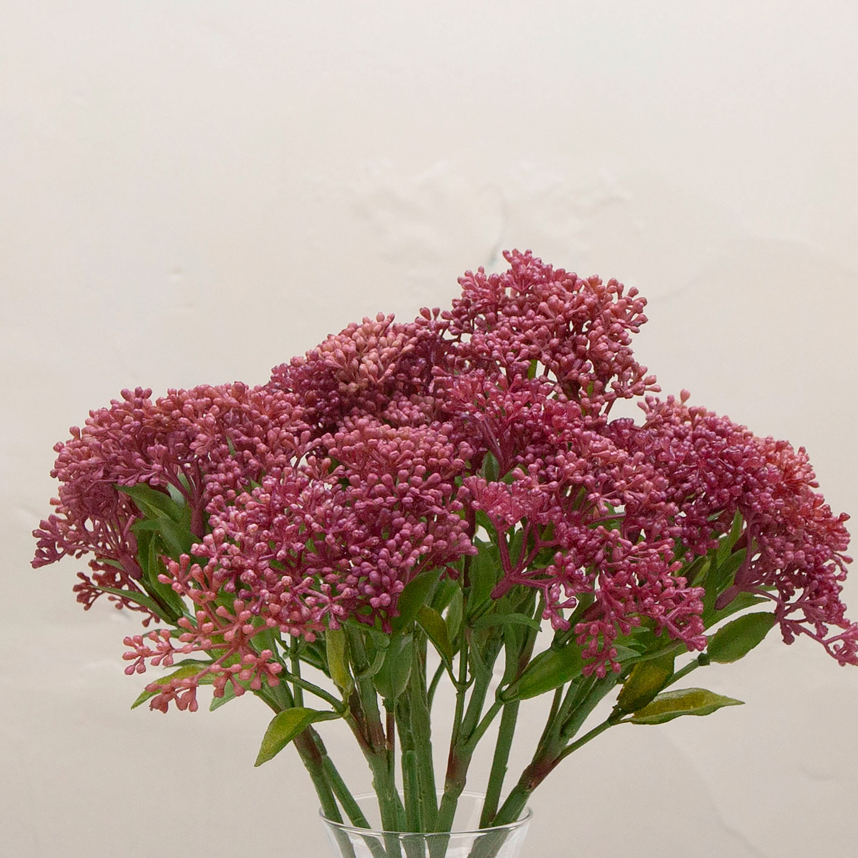 Close-up of artificial deep berry pink skimmia buds showing dense clusters and rich colour detail.