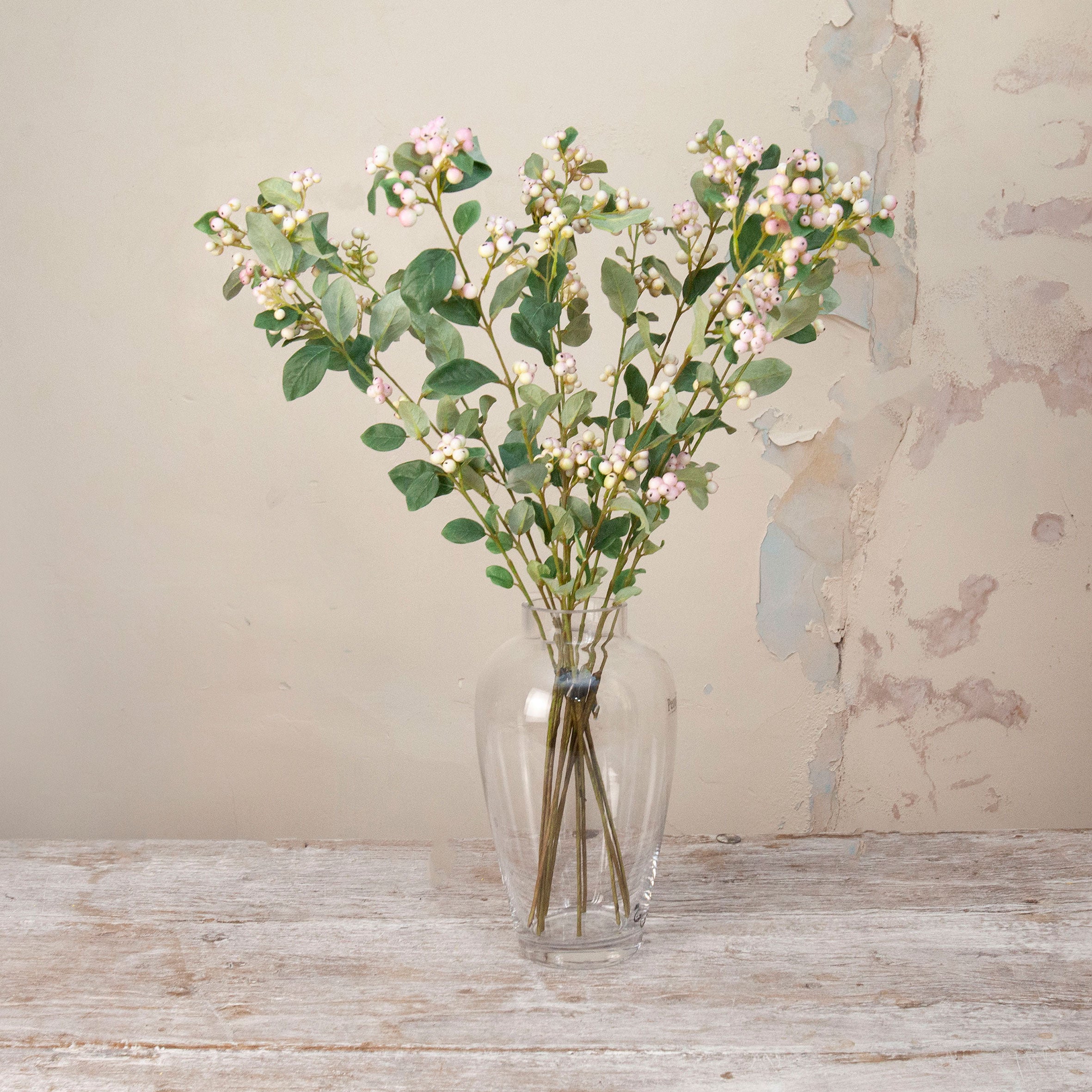 Artificial Snowberry Stems with soft pink and white berry clusters and realistic green foliage displayed in a clear glass vase