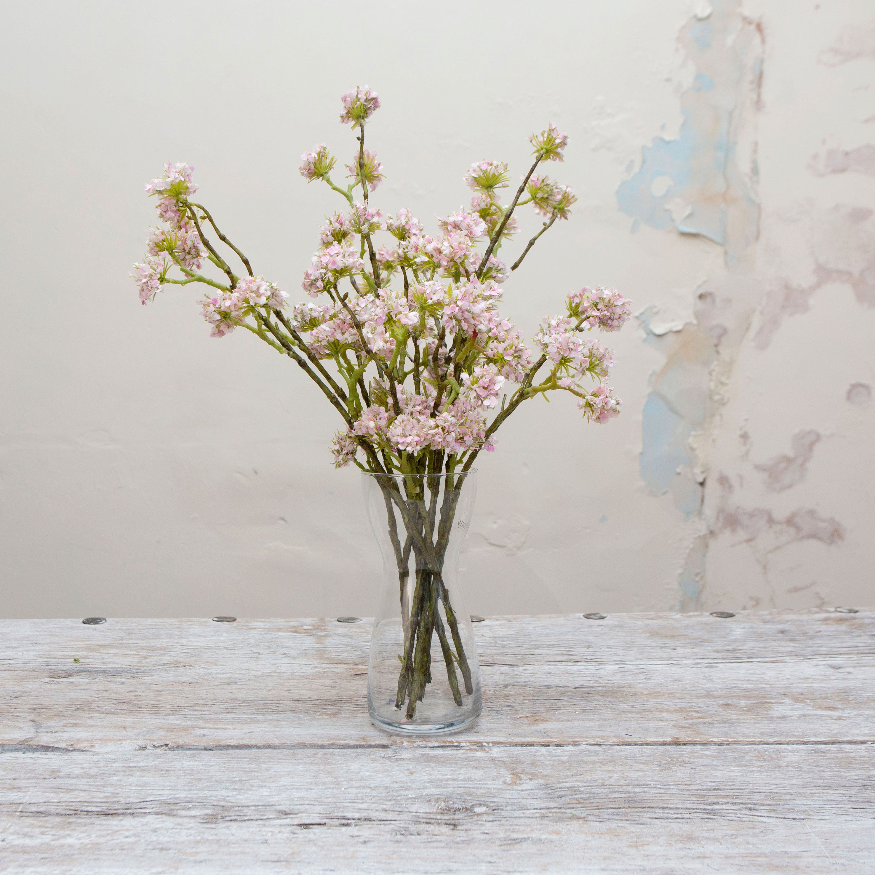 Artificial pale pink buddleia spray stems displayed together in a vase for styling purposes.
