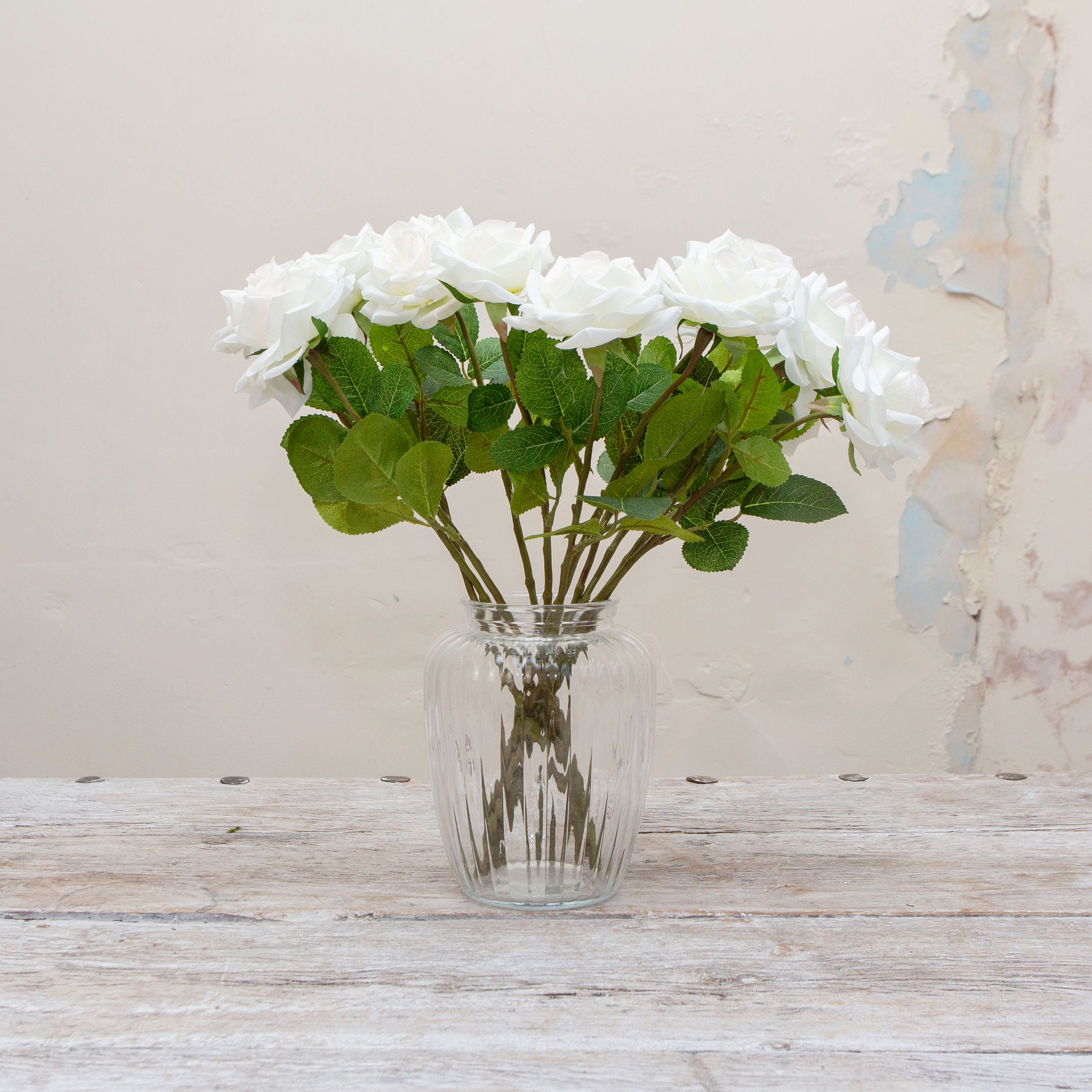 Artificial white rose stems displayed together in a vase for styling purposes