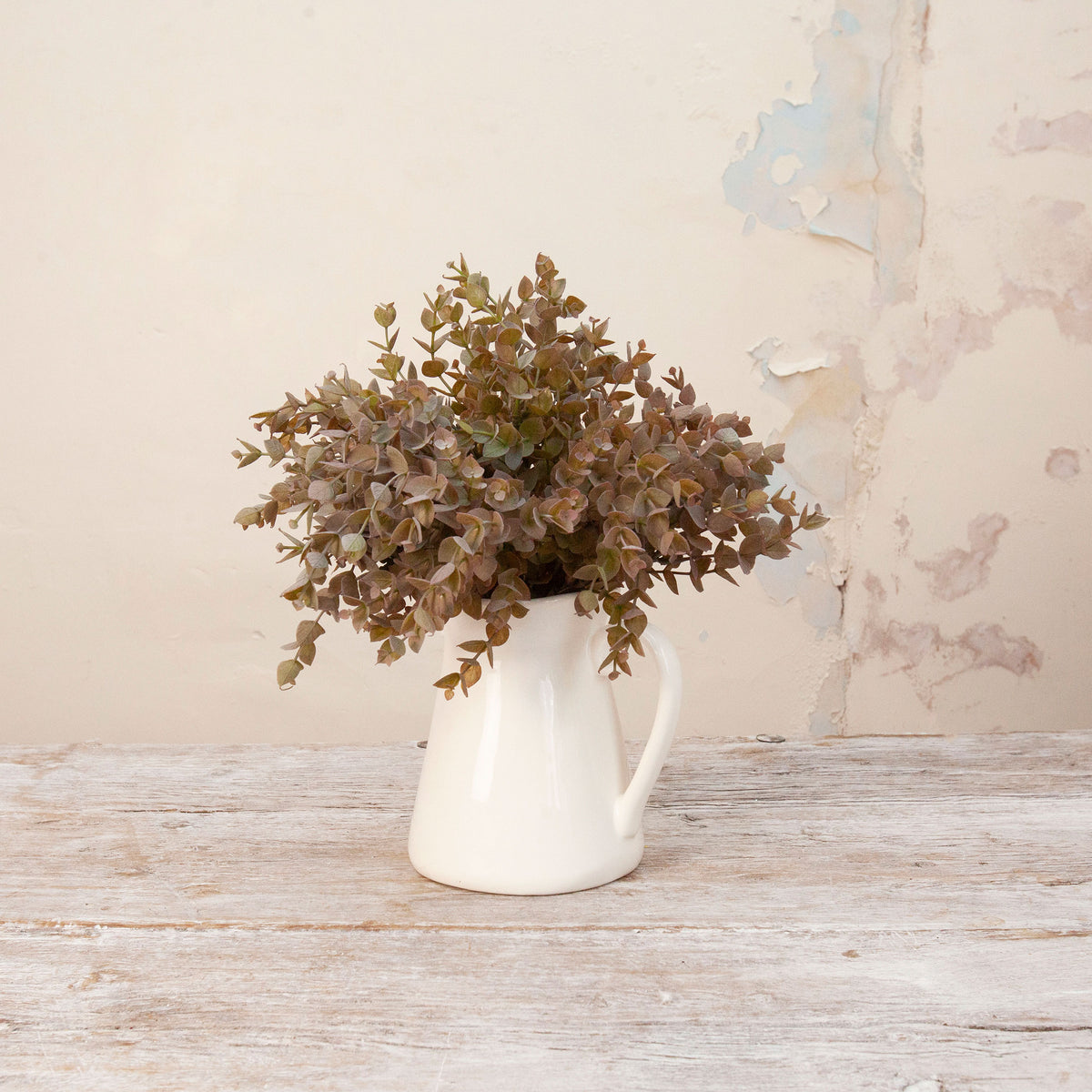 Artificial Mini Eucalyptus Bunch Stems with dense muted green and warm brown foliage displayed in a white ceramic jug