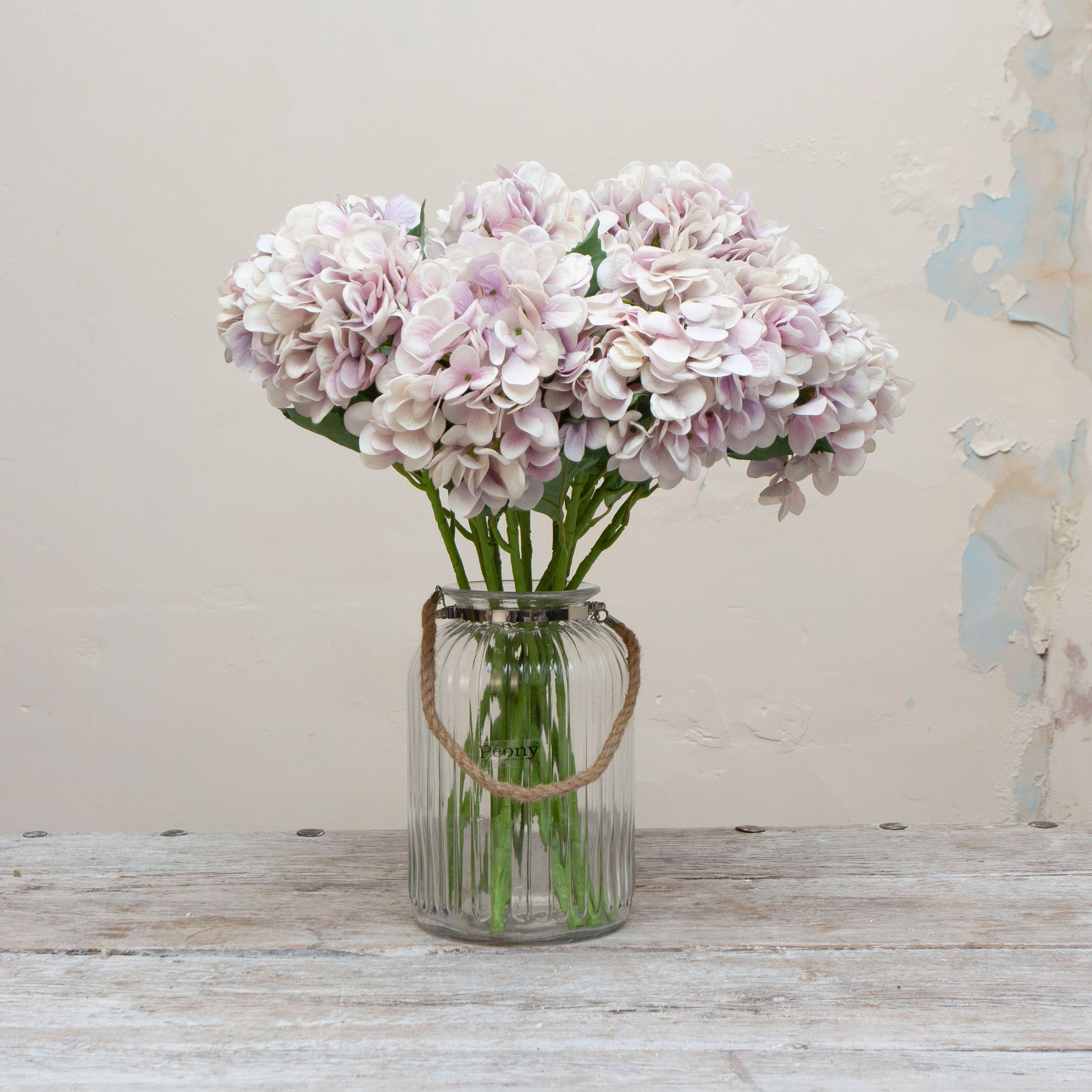 Artificial lilac hydrangea stems displayed in a vase, showcasing a large clustered bloom with gentle lavender tones and natural-looking foliage.”