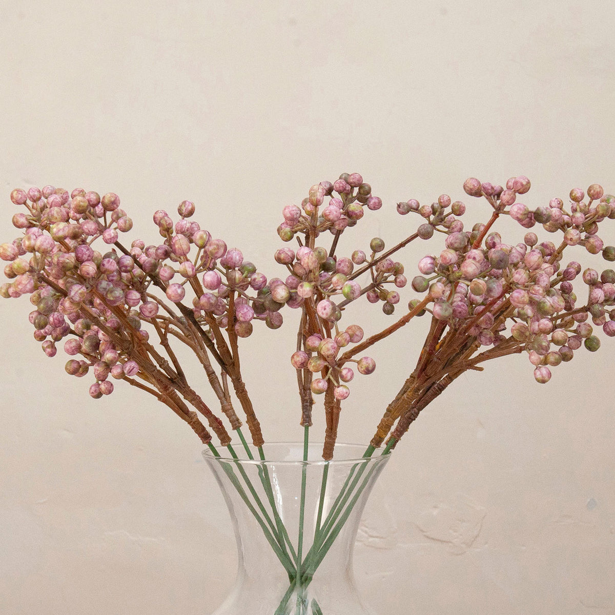 Close up of Artificial Berry Pick Stems with clusters of soft pink and mauve berries on natural brown branches displayed in a clear glass vase