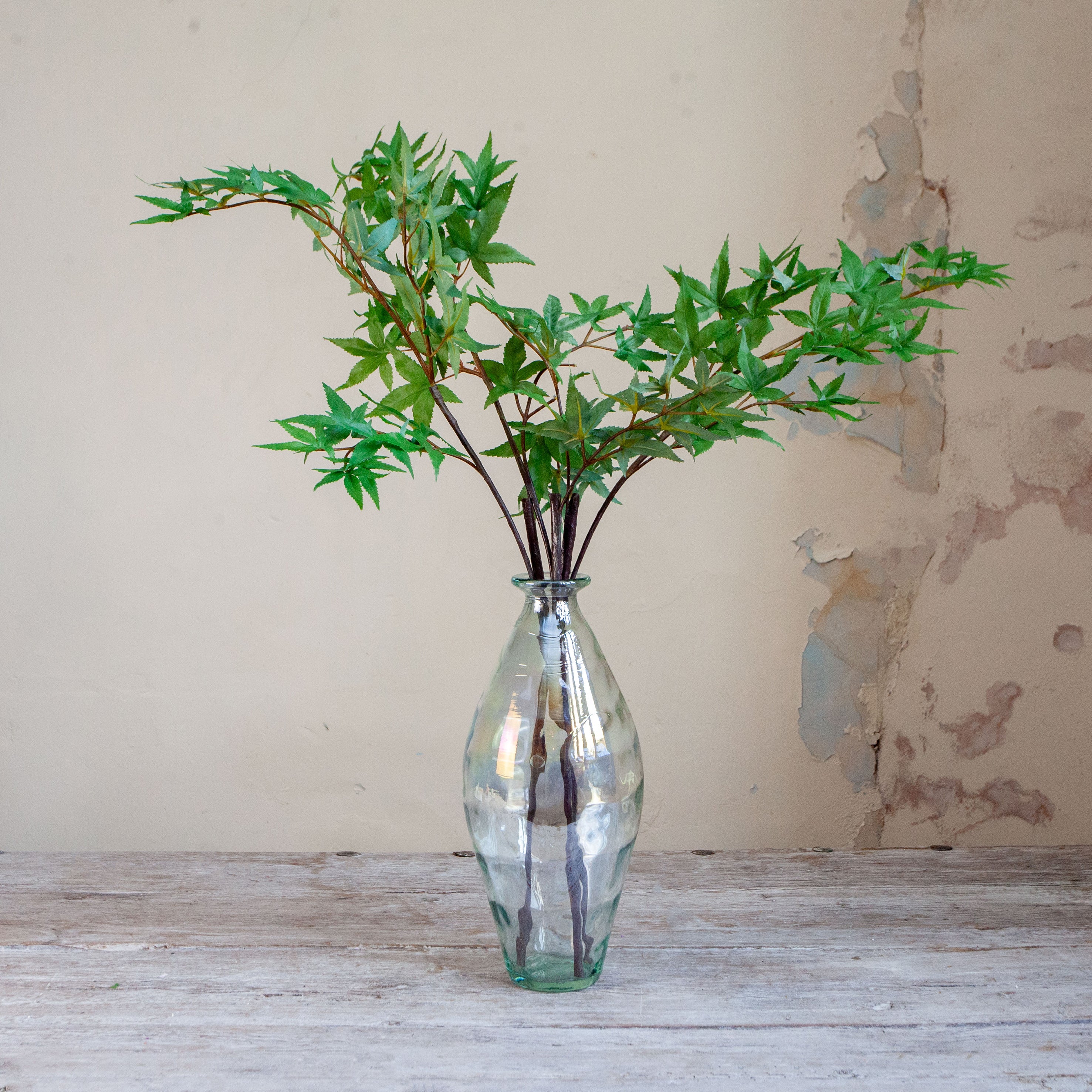 Artificial green maple leaves in a lustre bottle vase