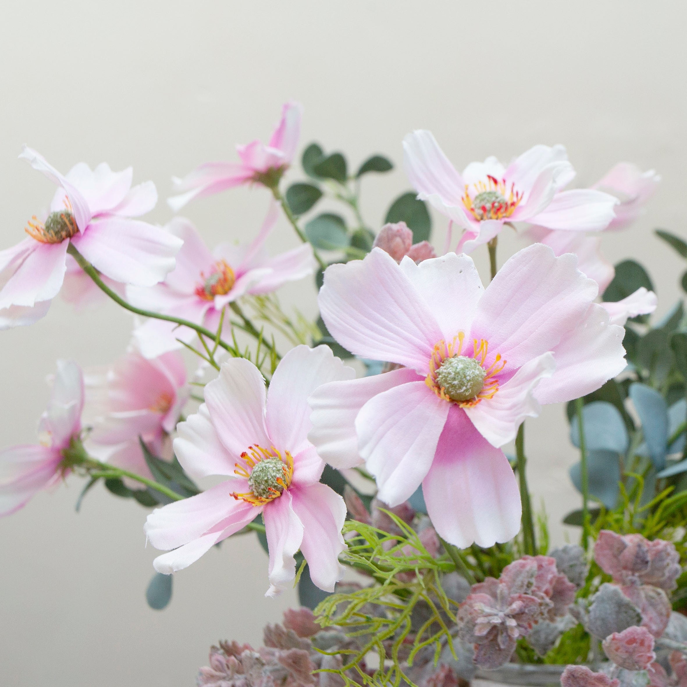 Artificial cosmos flower arrangement featuring soft pink blooms with eucalyptus and flocked greenery, displayed in a medium rope lantern vase