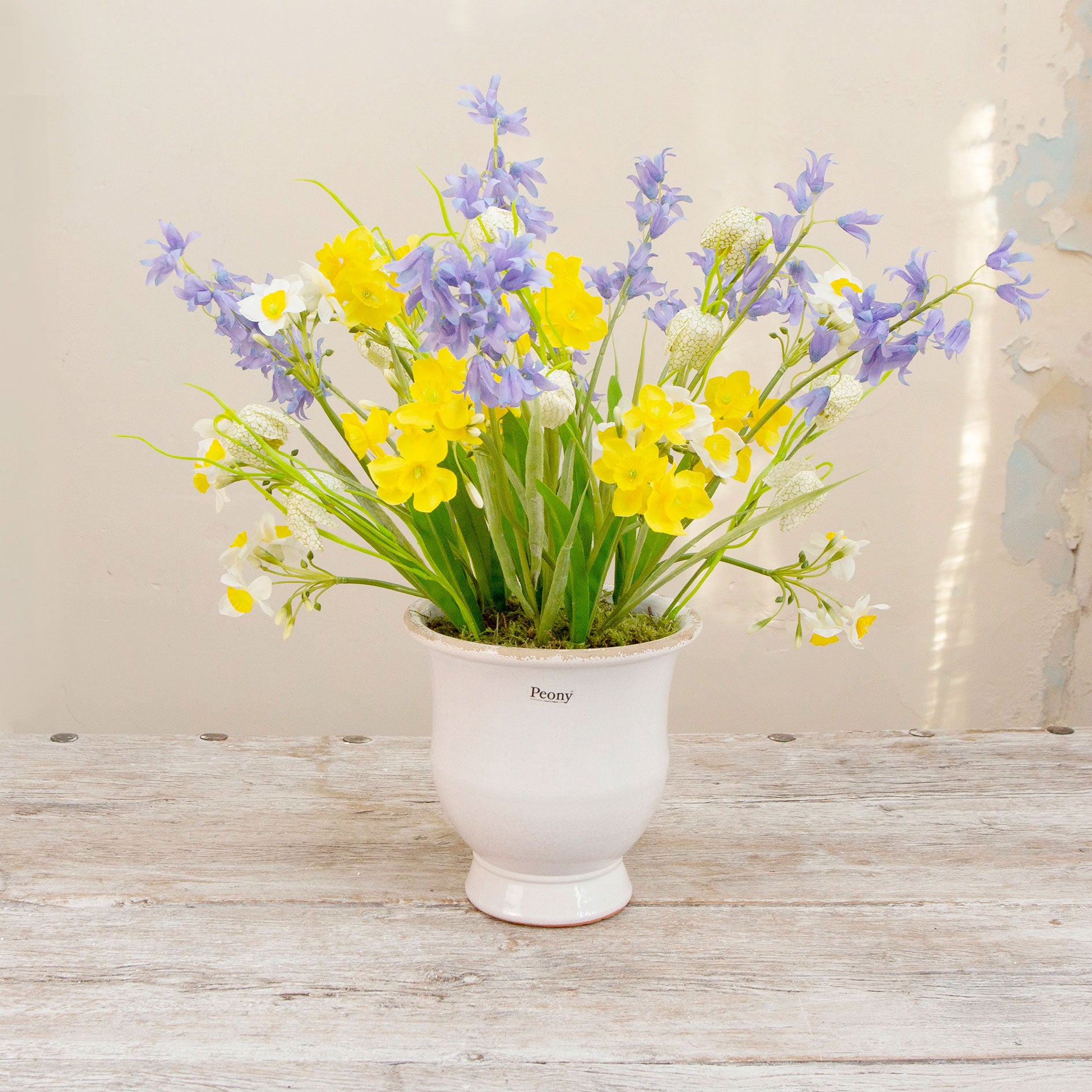 Artificial Spring flower arrangement with daffodils, bluebells and fritillaria in a white aged urn