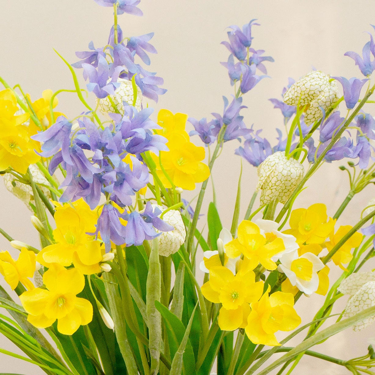 Close-up of an artificial spring flower arrangement with yellow daffodils, bluebells and fritillaria blooms.