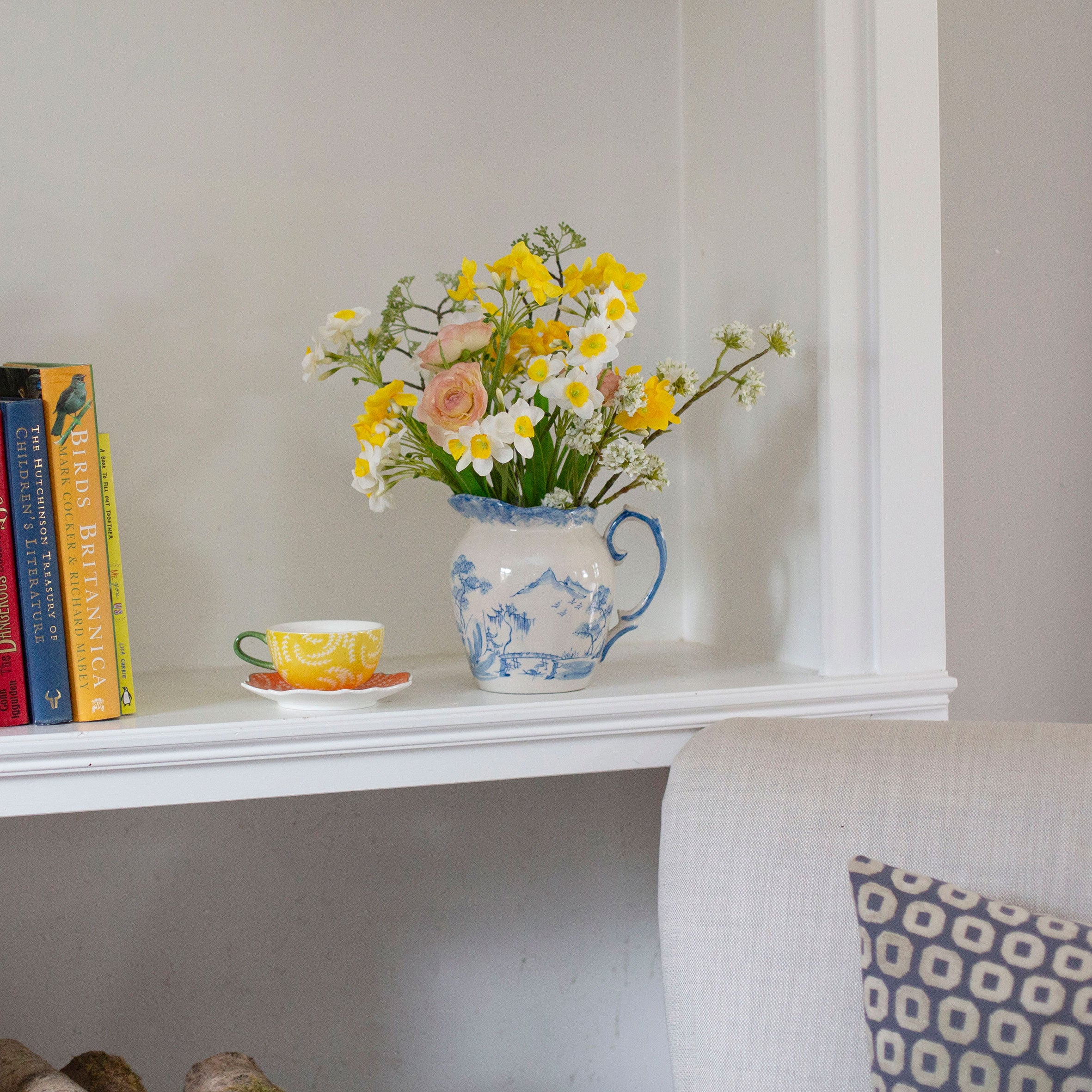 Artificial daffodil and ranunculus flower arrangement in a blue and white hand painted oriental jug