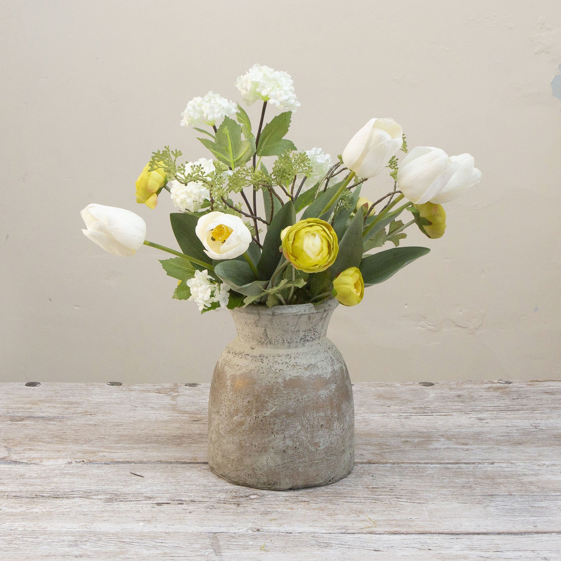 Artificial tulip and ranunculus flower arrangement in a rustic Roman style pot