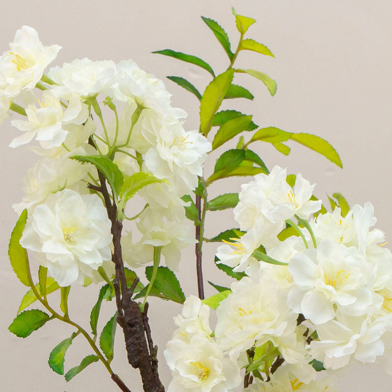 Artificial blossom stems arranged in a clear glass milk bottle vase