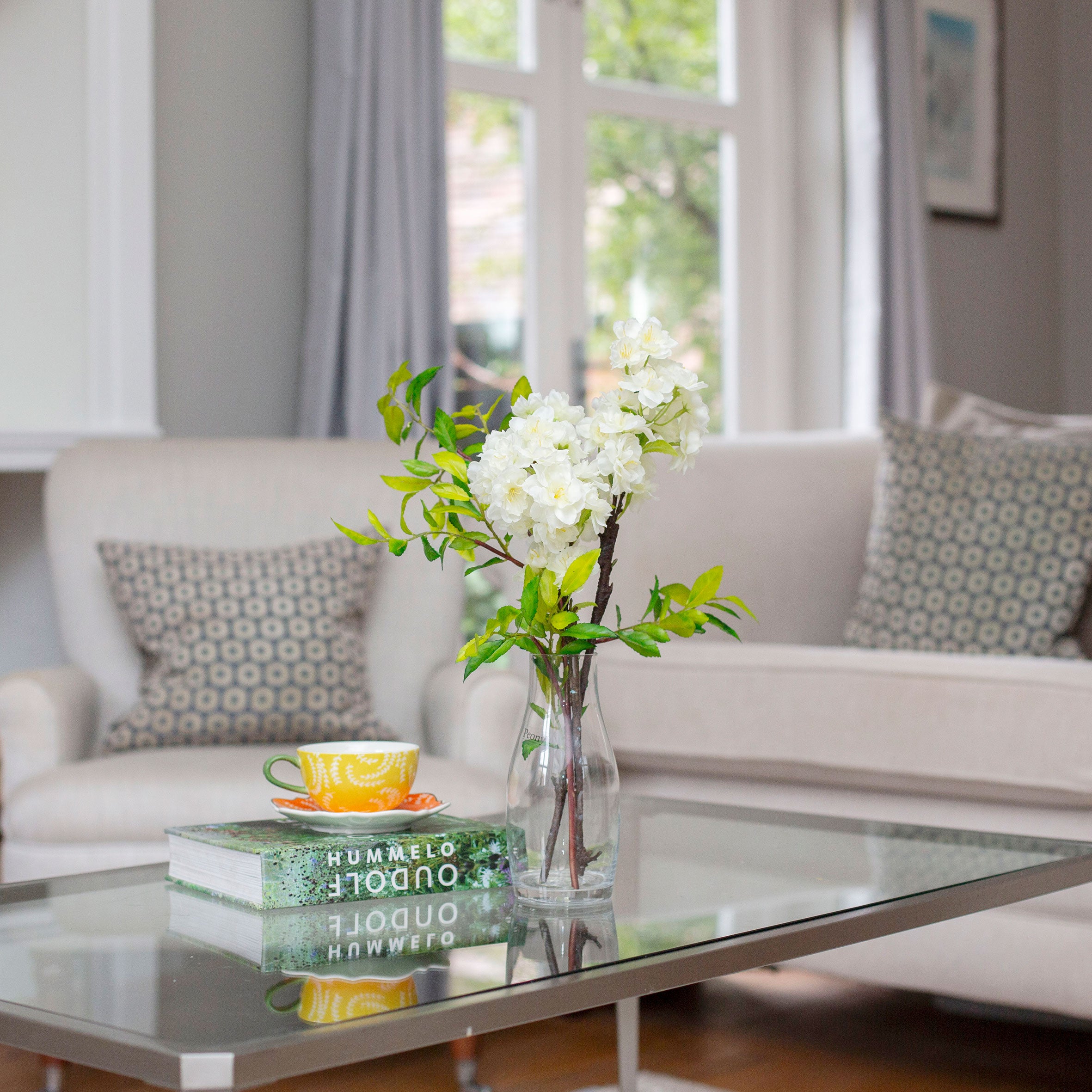 Artificial blossom stems arranged in a clear glass milk bottle vase
