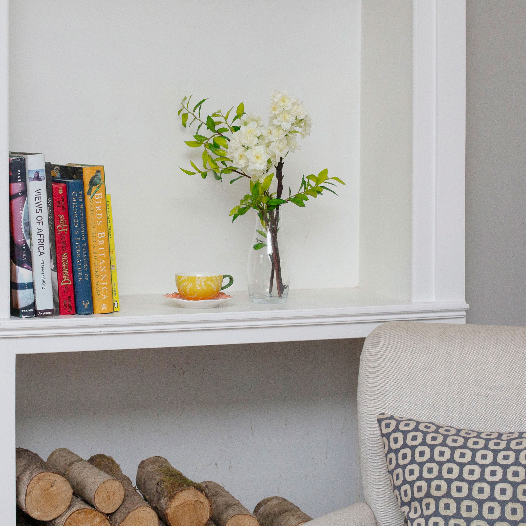 Artificial blossom stems arranged in a clear glass milk bottle vase