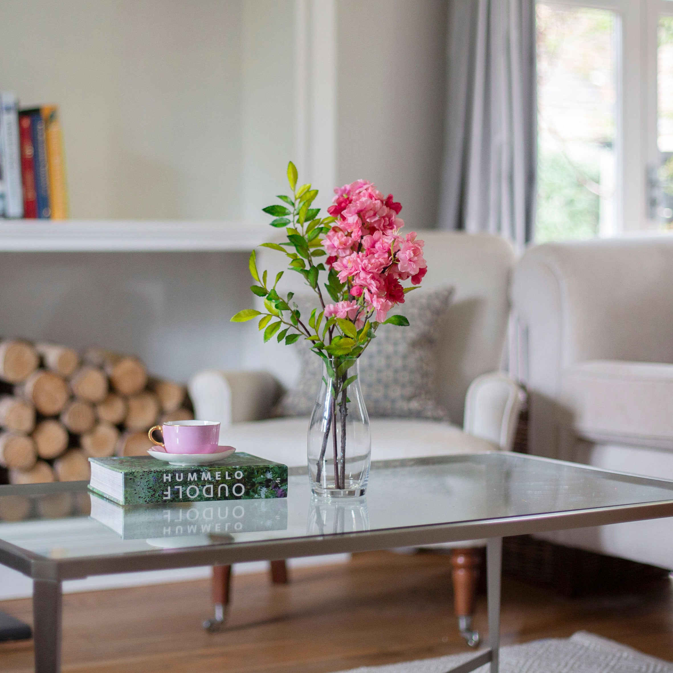 Artificial blossom stems arranged in a clear glass milk bottle vase