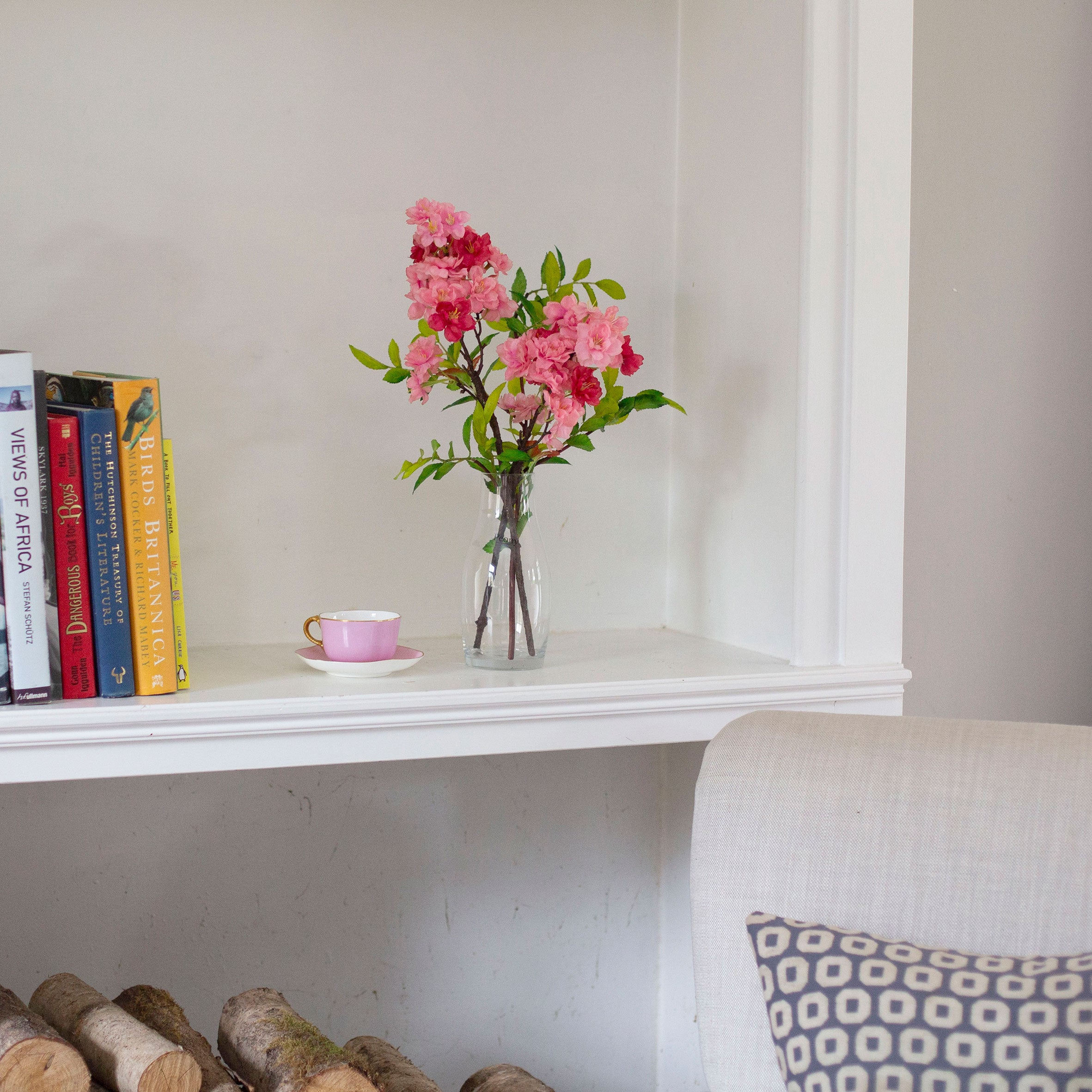 Artificial blossom stems arranged in a clear glass milk bottle vase