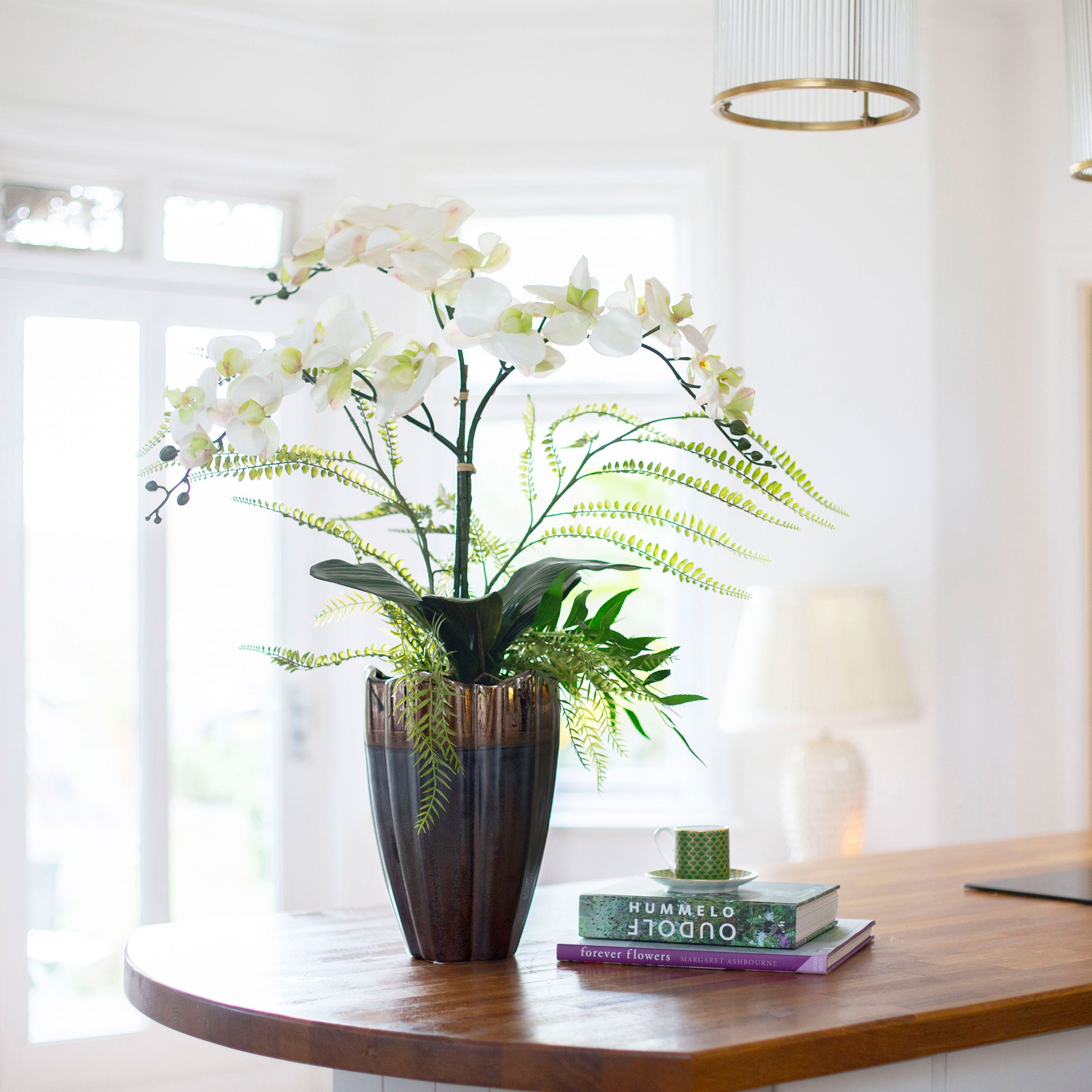 Artificial phalaenopsis orchid and ferns arranged in a tall lotus style pot