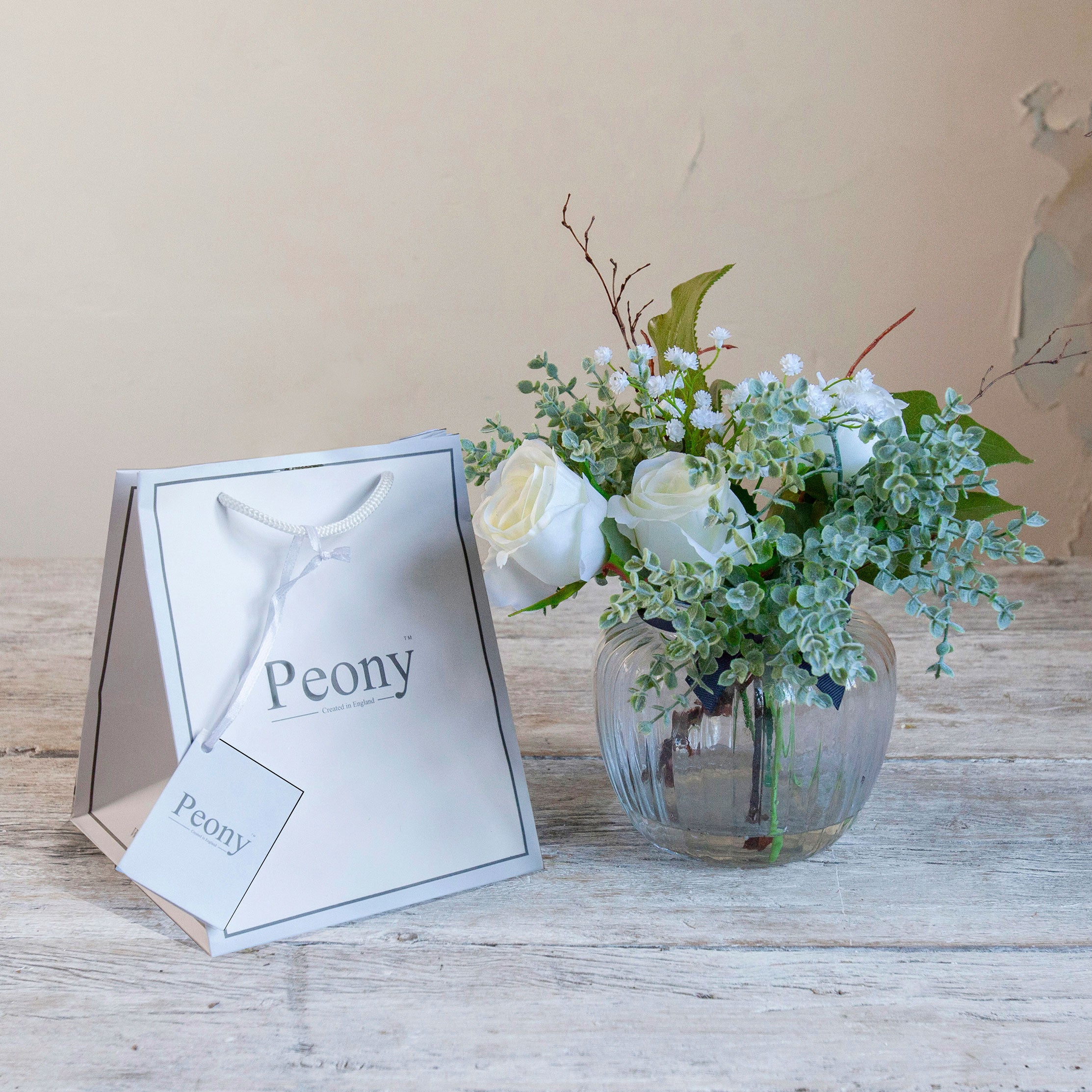 Artificial white roses, mini eucalyptus and gypsophila set in a clear optic glass jar vase with Peony gift bag.