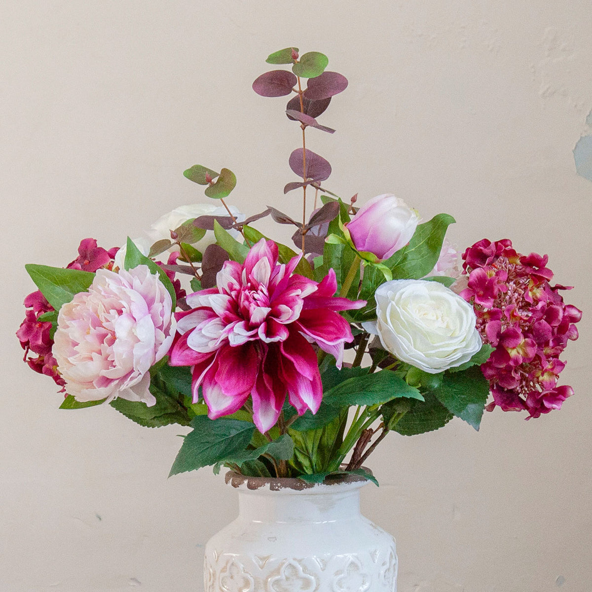 Close-up of an artificial hydrangea, dahlia and peony bouquet in pink, burgundy and white tones with realistic foliage.