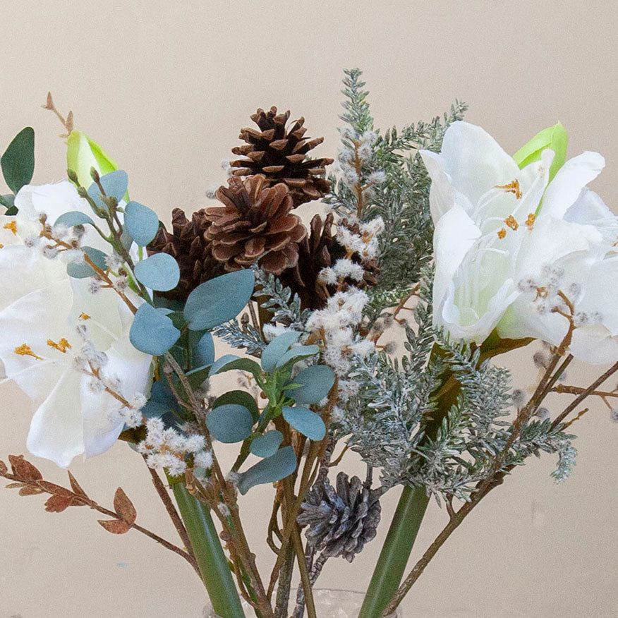 Close up of Artificial Amaryllis, Pine Cone & Eucalyptus Arrangement with white amaryllis blooms, brown pine cones, frosted winter foliage and eucalyptus