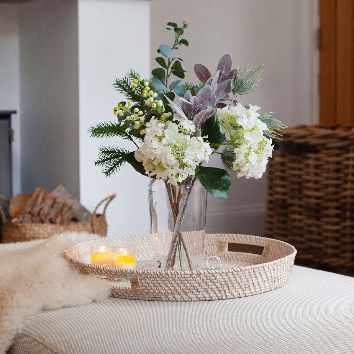 Lifestyle photo of Artificial Seeded Hydrangea, Berries & Pine Cone Bouquet with white hydrangea blooms, green berries, eucalyptus, pine foliage and natural pine cone accents displayed in a clear glass vase