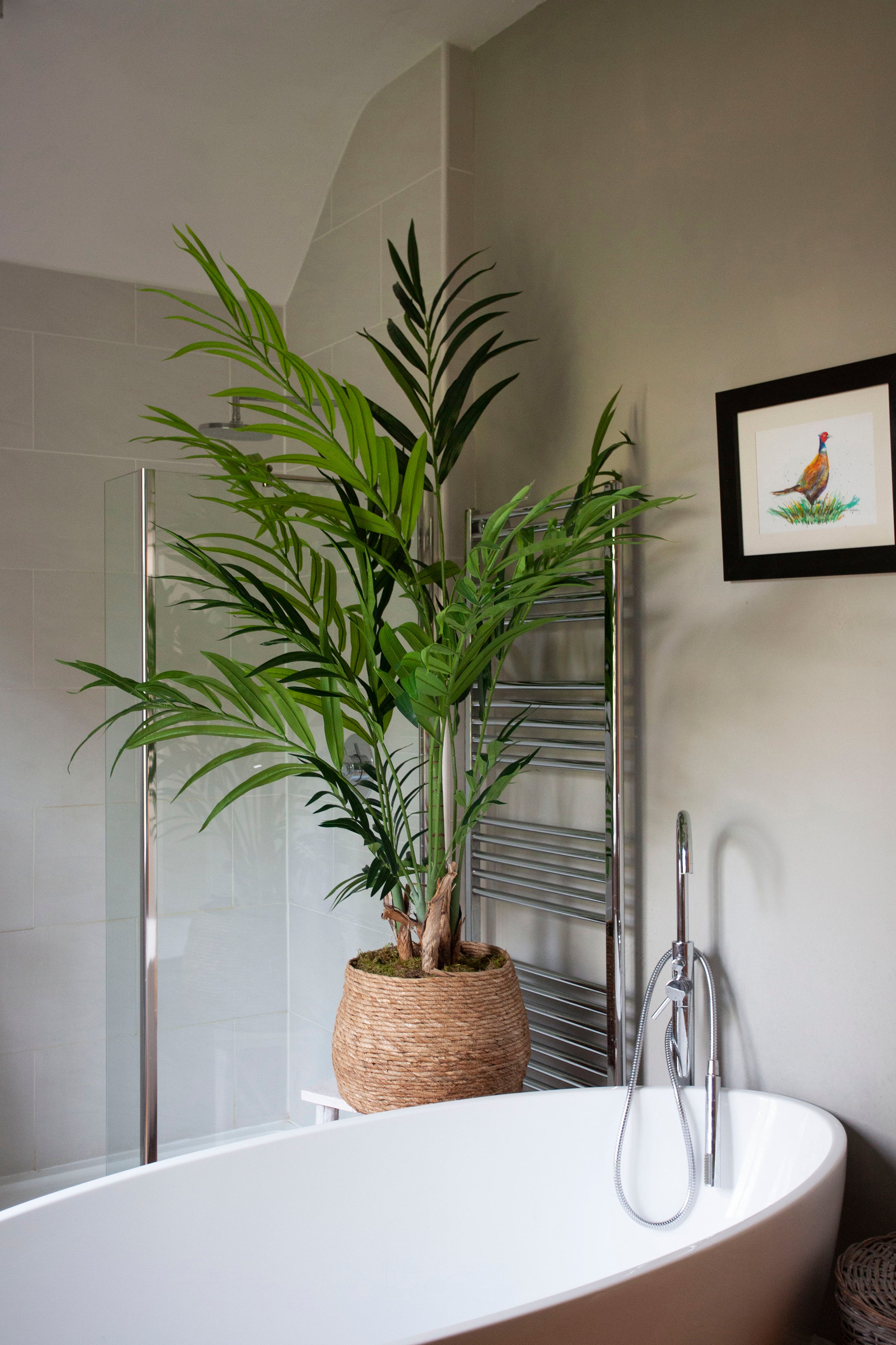 Artificial Kentia palm with lush green fronds and natural variation, planted with real moss and displayed in a hand-woven basket planter.