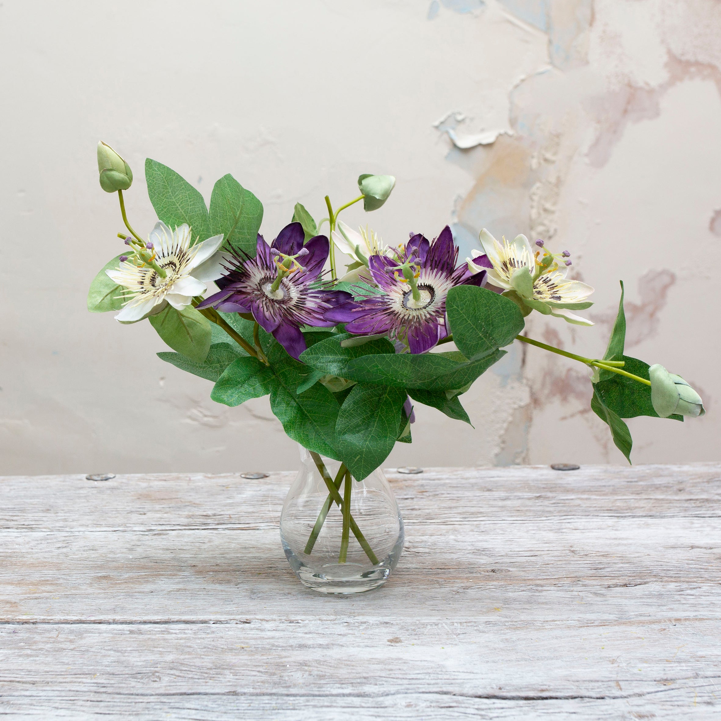 Artificial passion flower stem displayed in a small clear glass vase for styling purposes only