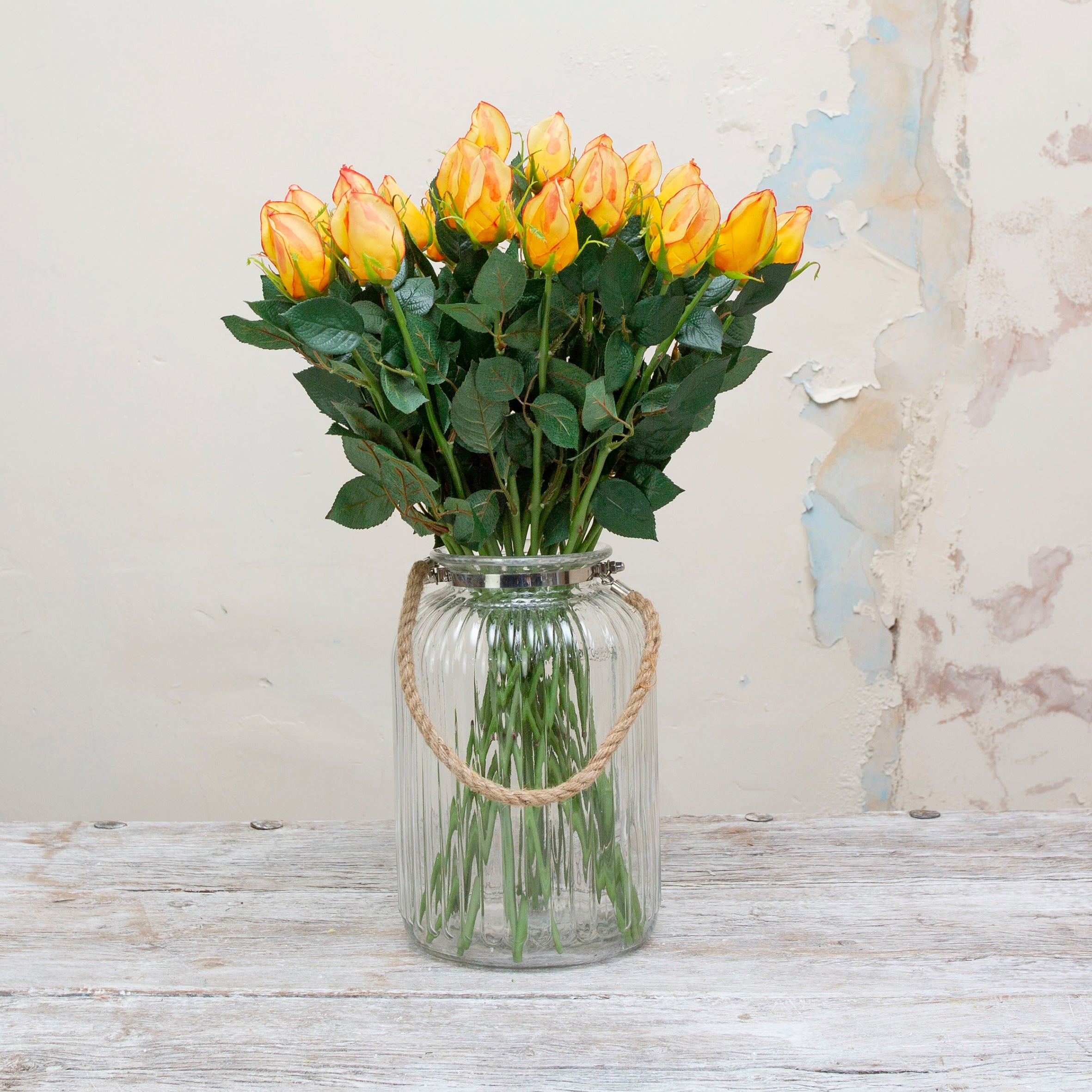 Yellow rose bud with a hint of red with leaves. Peony