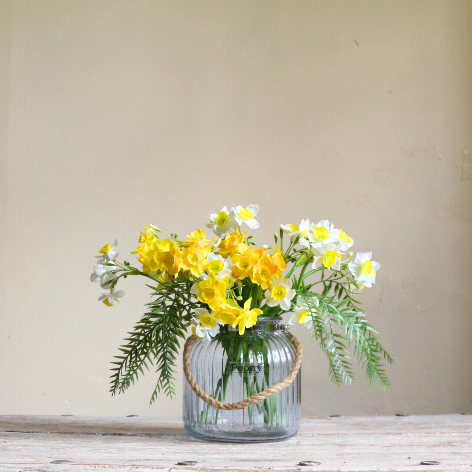 Artificial narcissus and willow arrangement with white spring blooms and sculptural branches, displayed in a rope lantern vase.