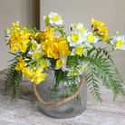 Artificial narcissus and willow arrangement with white spring blooms and sculptural branches, displayed in a rope lantern vase.