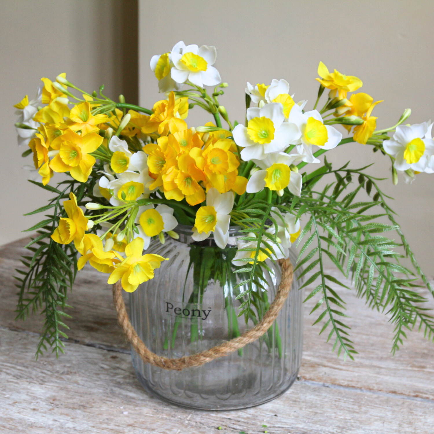 Artificial narcissus and willow arrangement with white spring blooms and sculptural branches, displayed in a rope lantern vase.