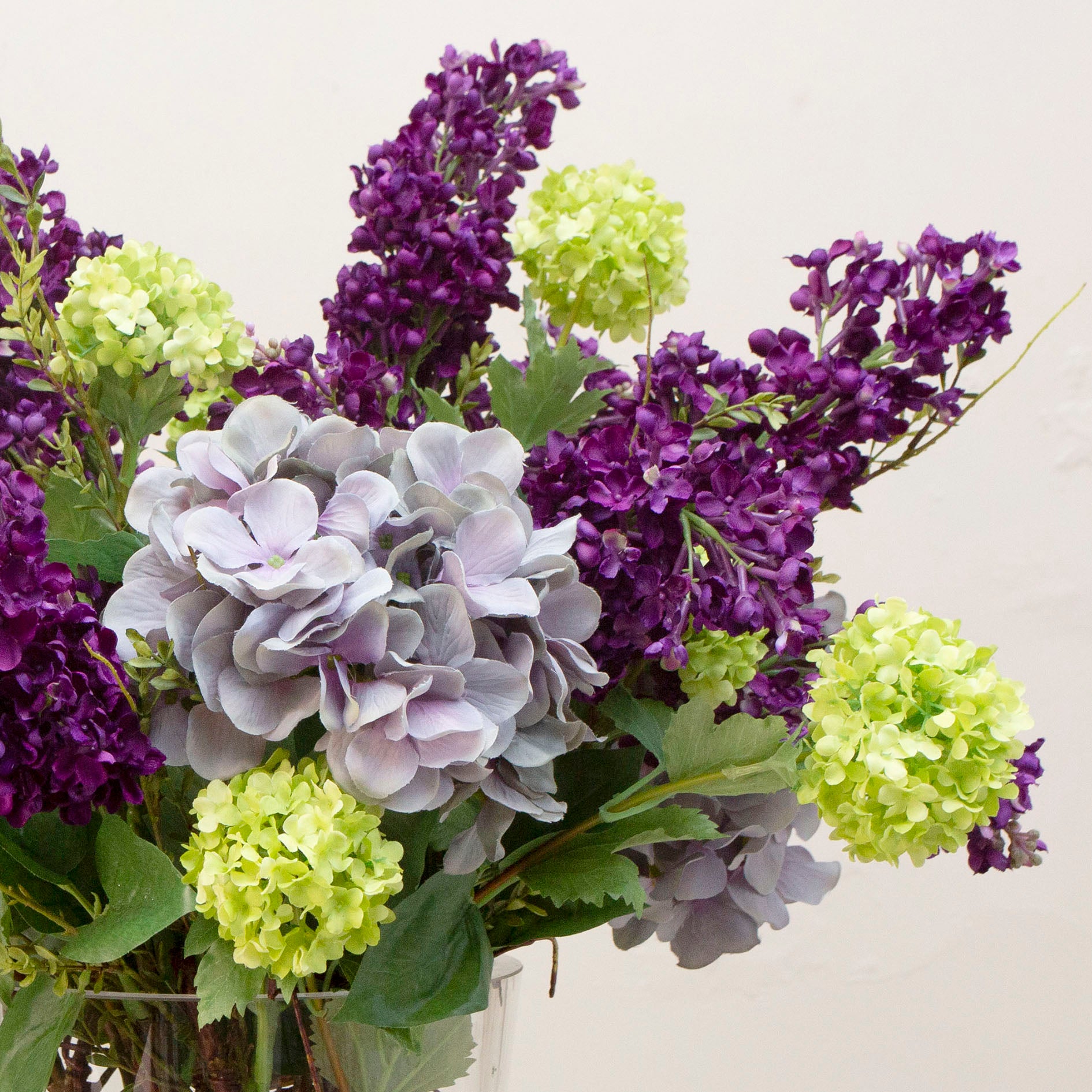 Artificial lilac and viburnum arrangement  in a clear glass vase