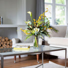 Artificial protea and calla lily arrangement with ferns, oncidium orchids and foliage in a clear glass vase