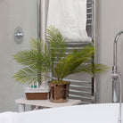 Artificial areca palm with realistic green fronds in a gold ceramic pot, styled in a modern bathroom.