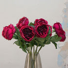 Close-up of artificial rose flower, showing deep red burgundy petals with layered texture, subtle tonal variation and realistic detailing.