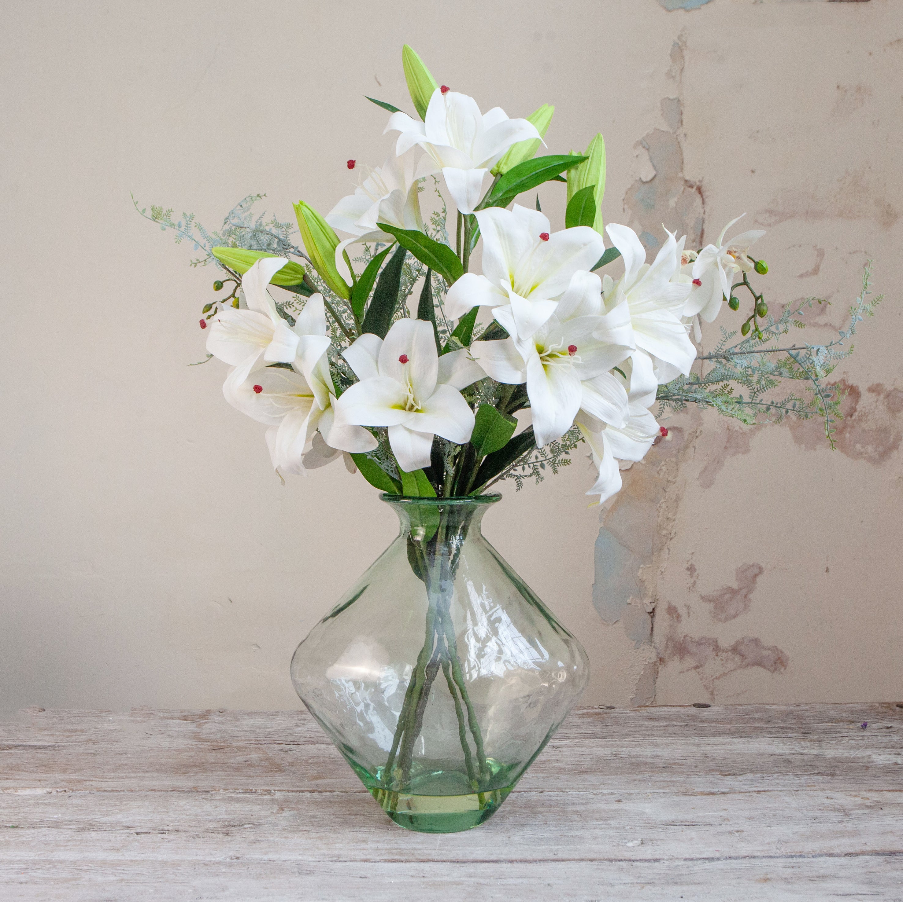 ARTIFICIAL WHITE ACSABLANCA LILES, WITH LACE FERN FOLAIGE IN A RECYCLED LUSTRE BOTTLE VASE