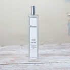 A bottle of 'Peony Wild Orchid' fragrance with a white label on a wooden surface.