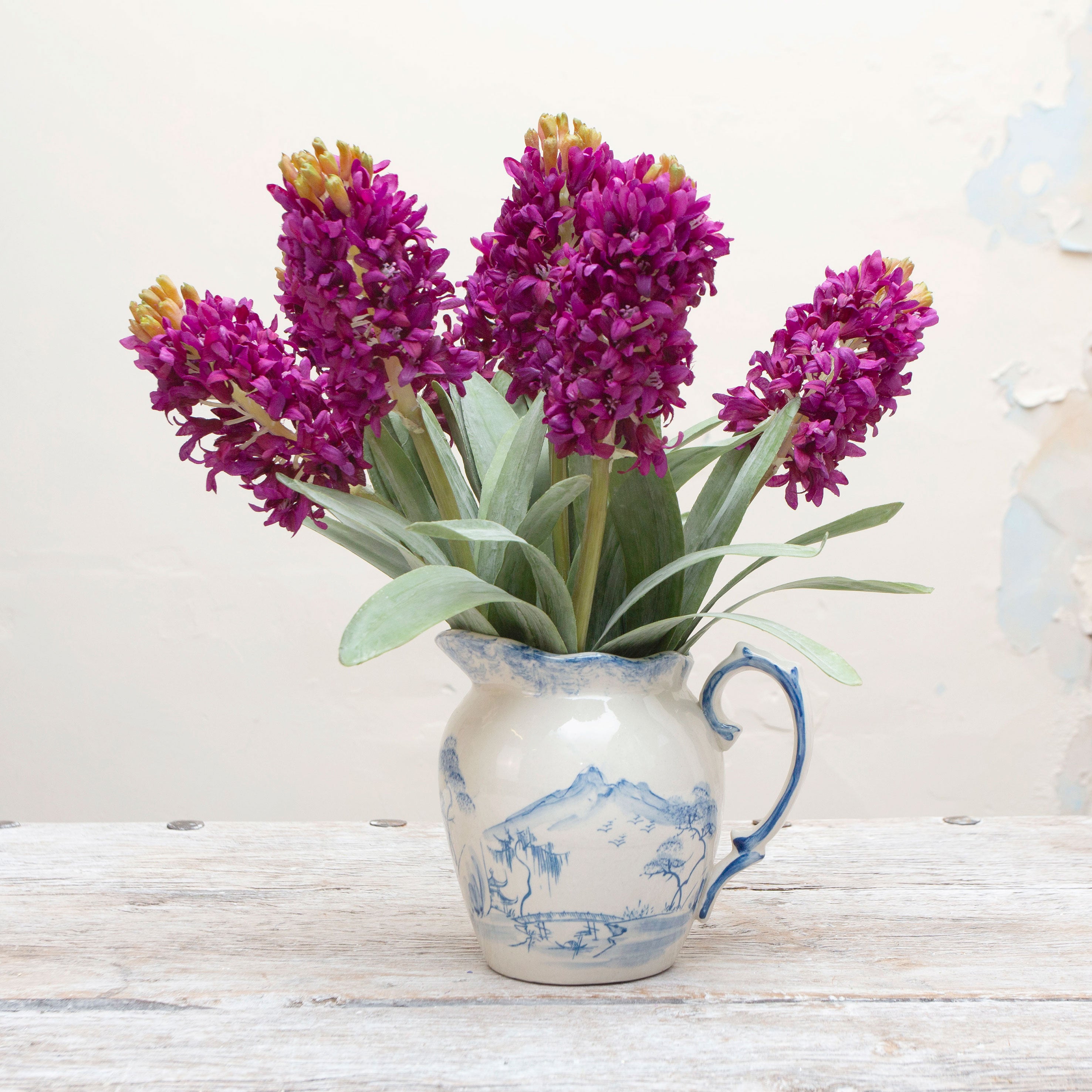 Artificial purple hyacinth stems displayed together in a vase for styling purposes.